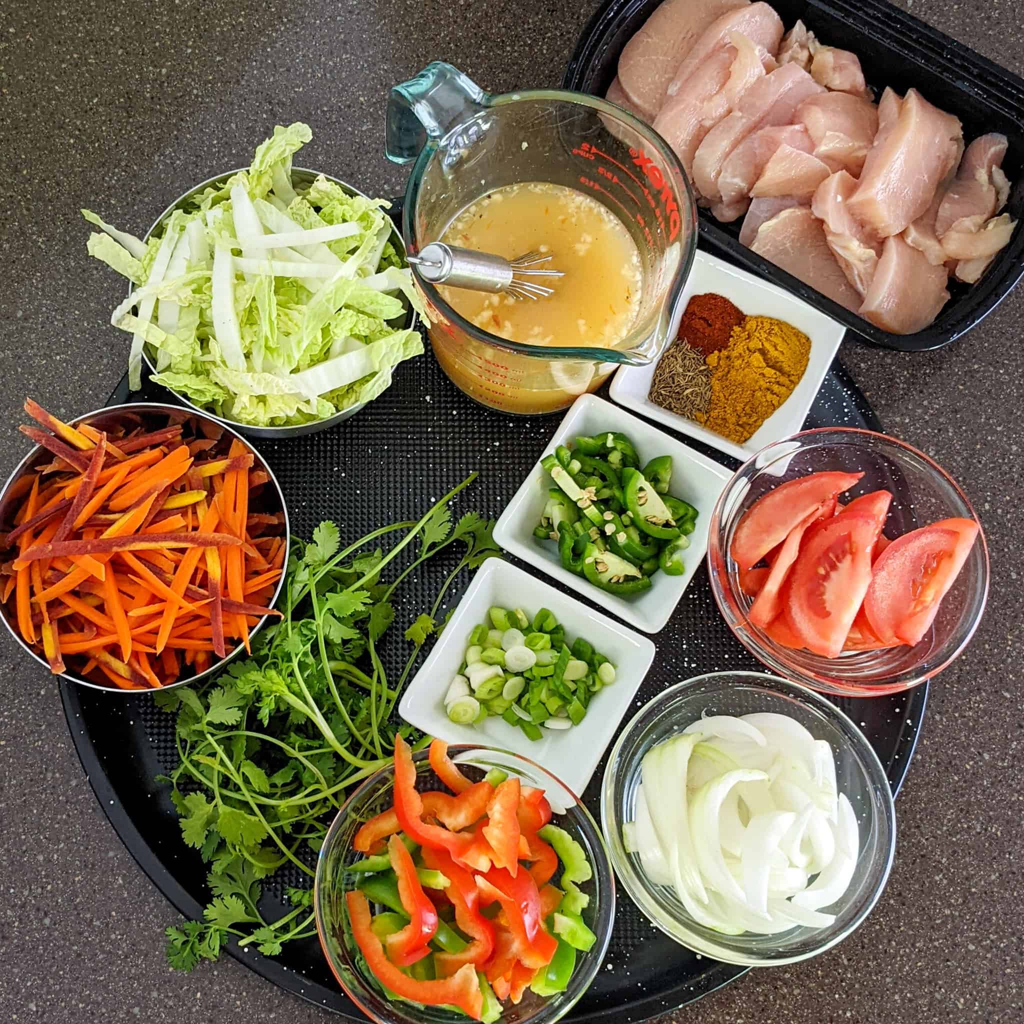 Ingredients for the curry chicken stir fry on a round tray in containers.