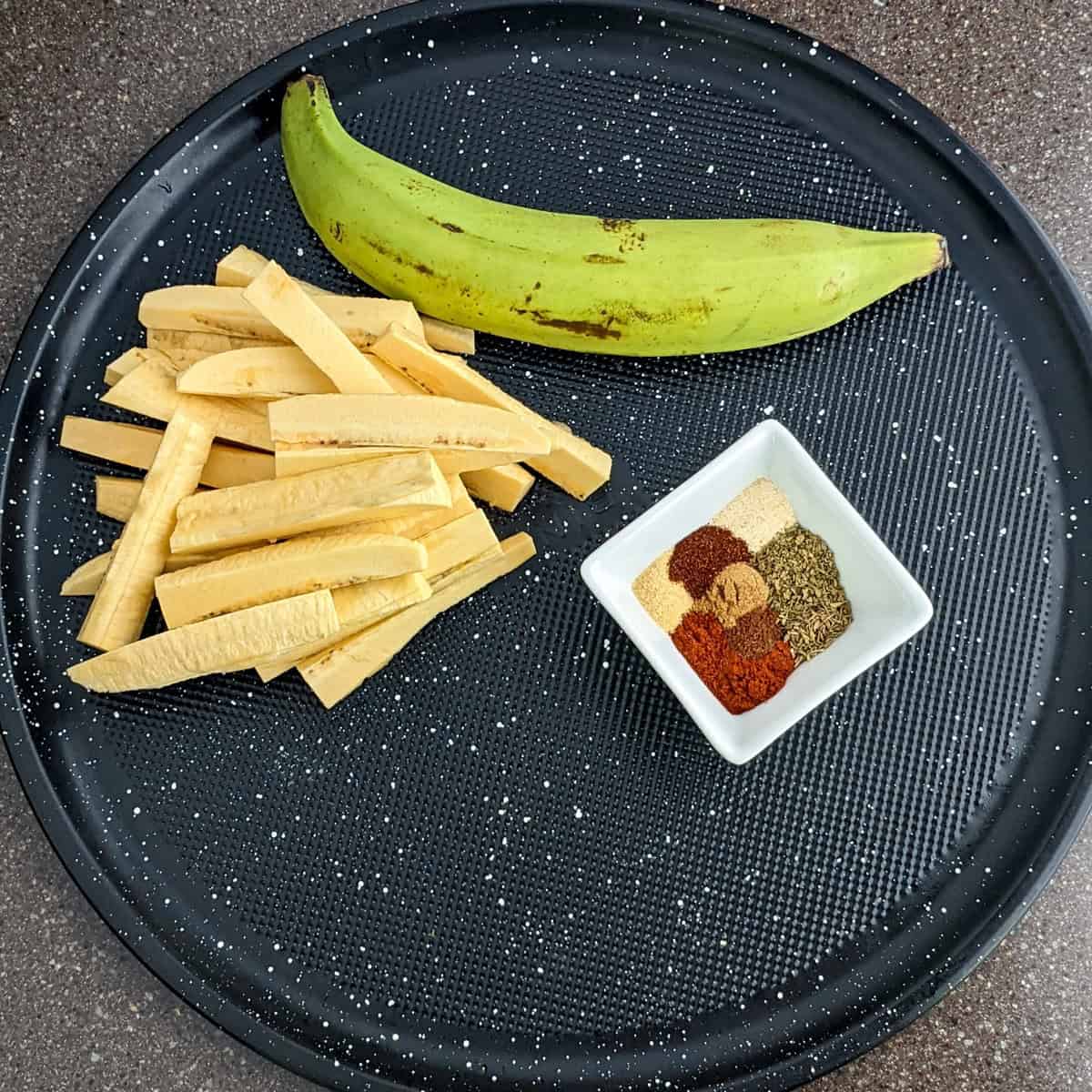 a whole plantain next to plantain cut into fries and spices.