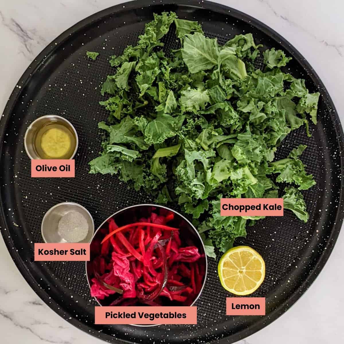 ingredients for the massaged kale salad on a round tray.