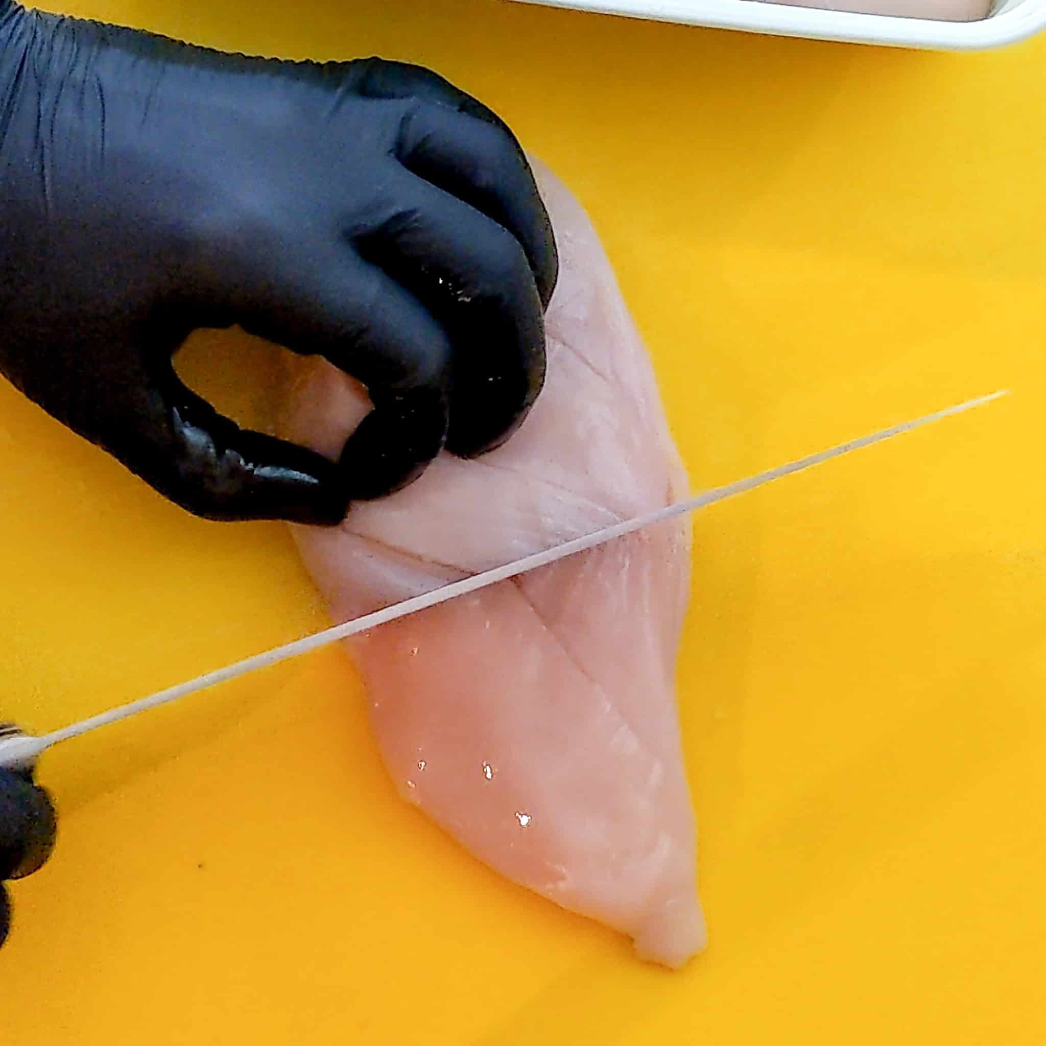 slitting chicken breast on a different angle with a knife.