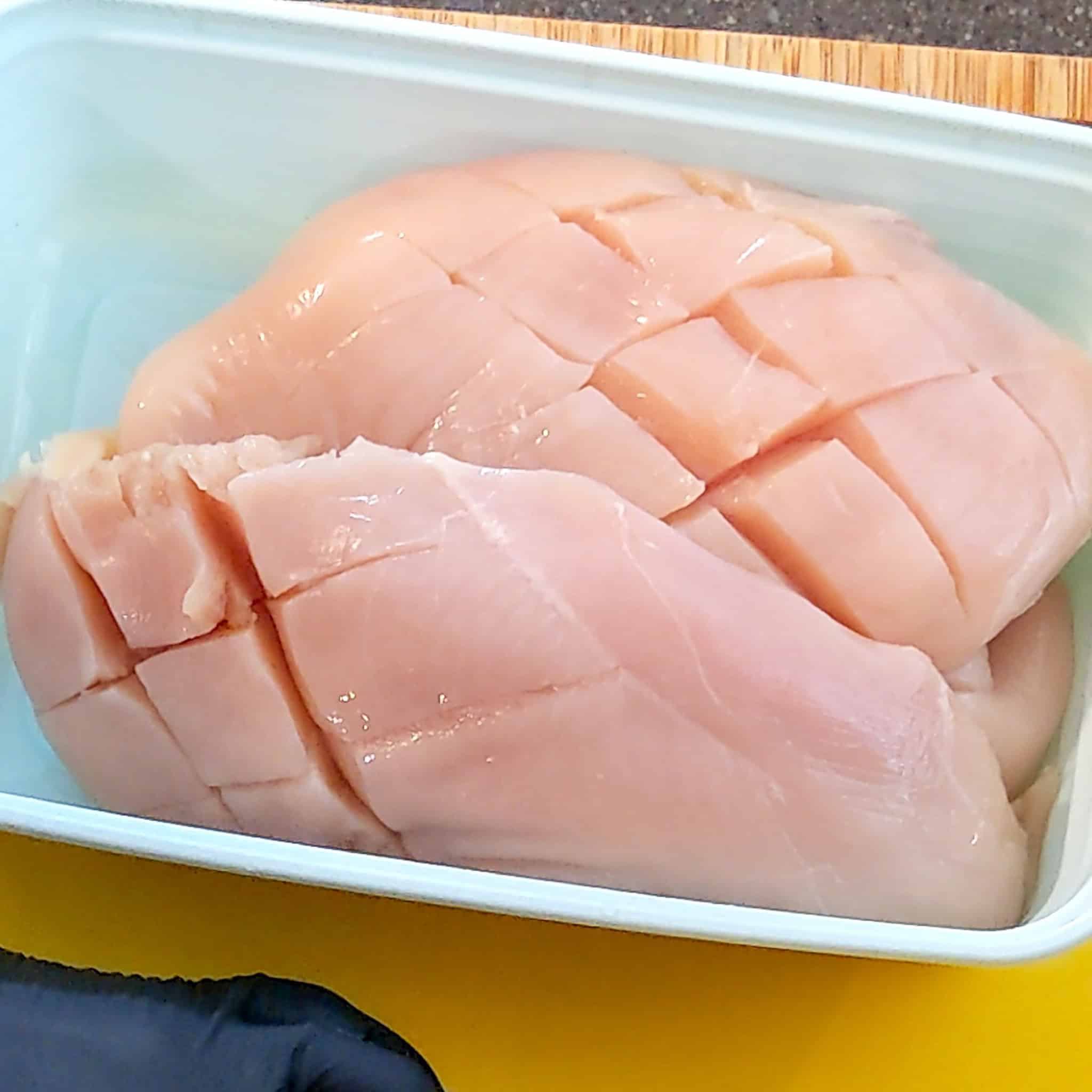 Diamond slit chicken breasts in a plastic container.