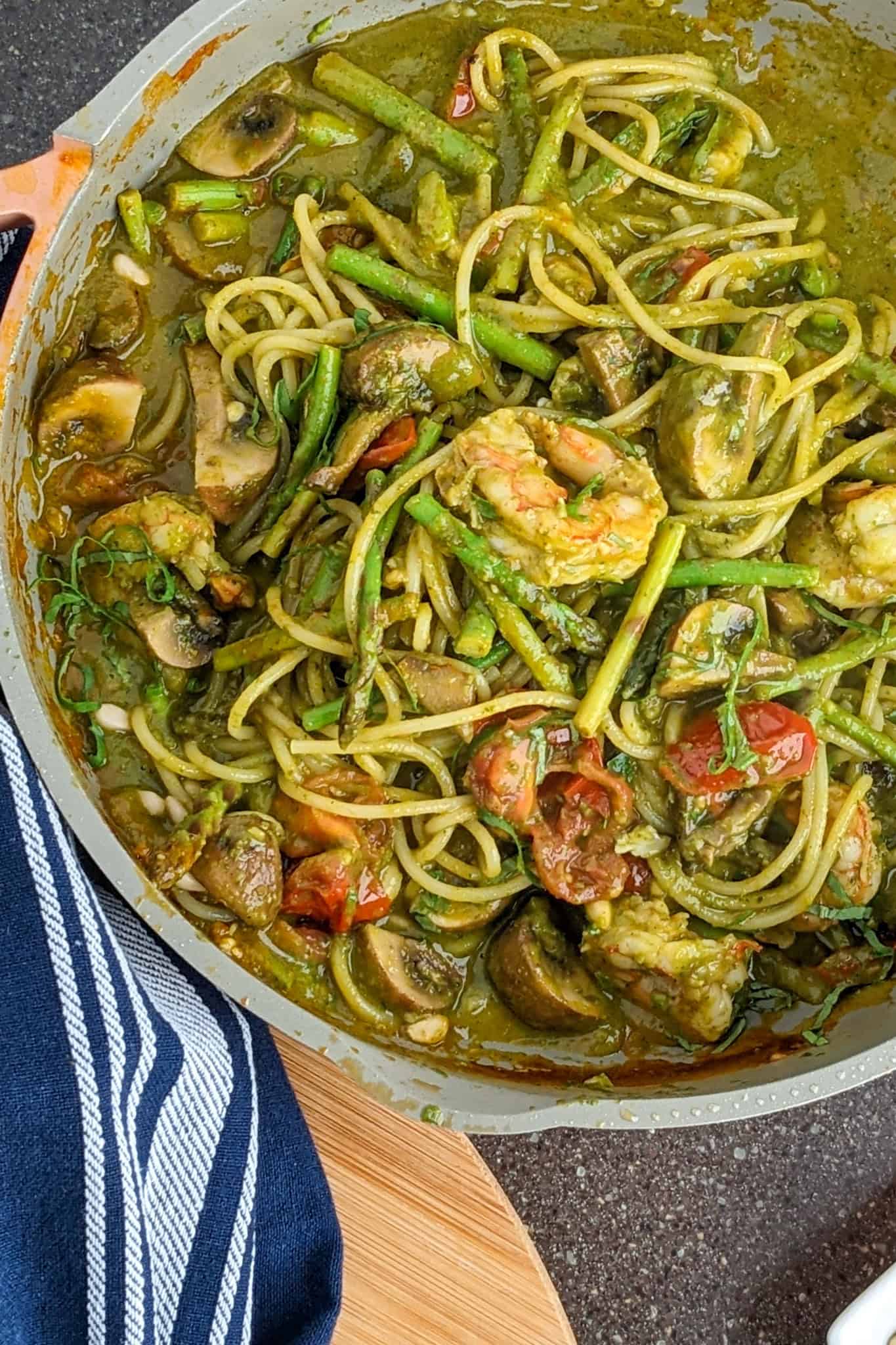 Vibrant Argentinian shrimp pesto pasta with fresh vegetables and a rich green sauce.