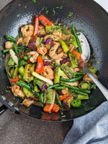 Vibrant shrimp stir-fry with colorful vegetables in a black wok, ready to serve.