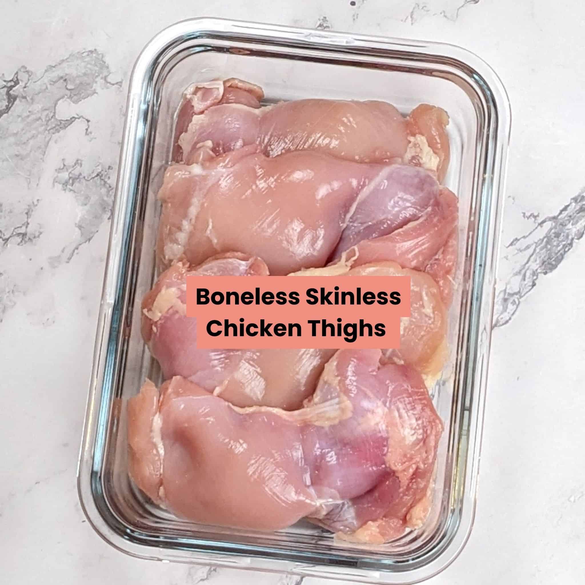 Fresh boneless skinless chicken thighs in a glass container.