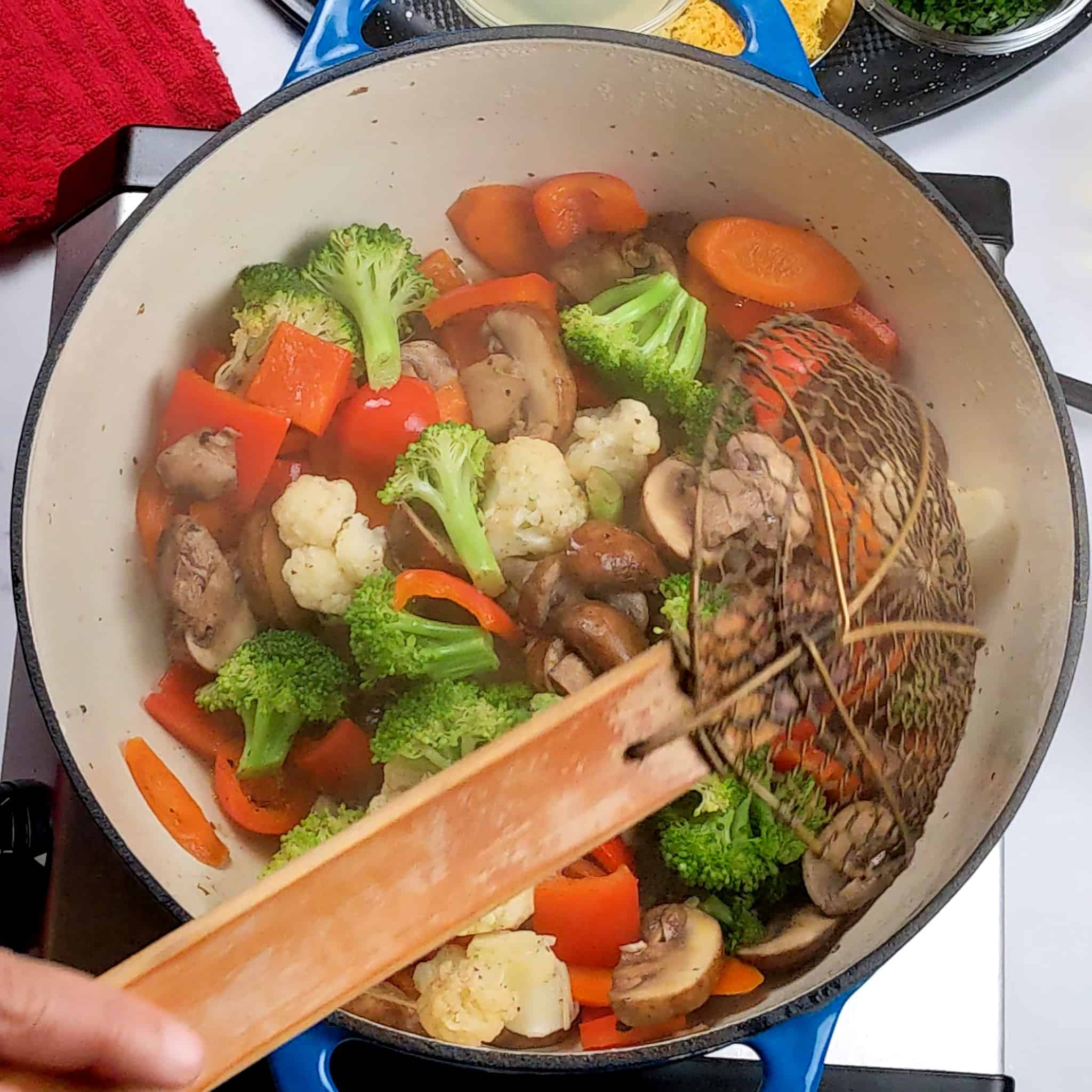 a wide wire strainer removing vegetables from the Dutch oven