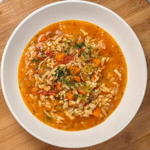 top view and close up the Lemon Calabrian Chili Chicken Orzo Soup in a wide rim bowl .