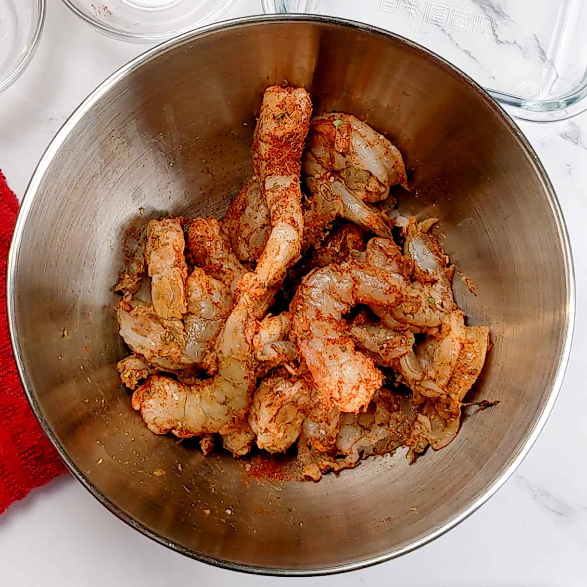seasoned raw shrimp in a stainless steel mixing bowl.
