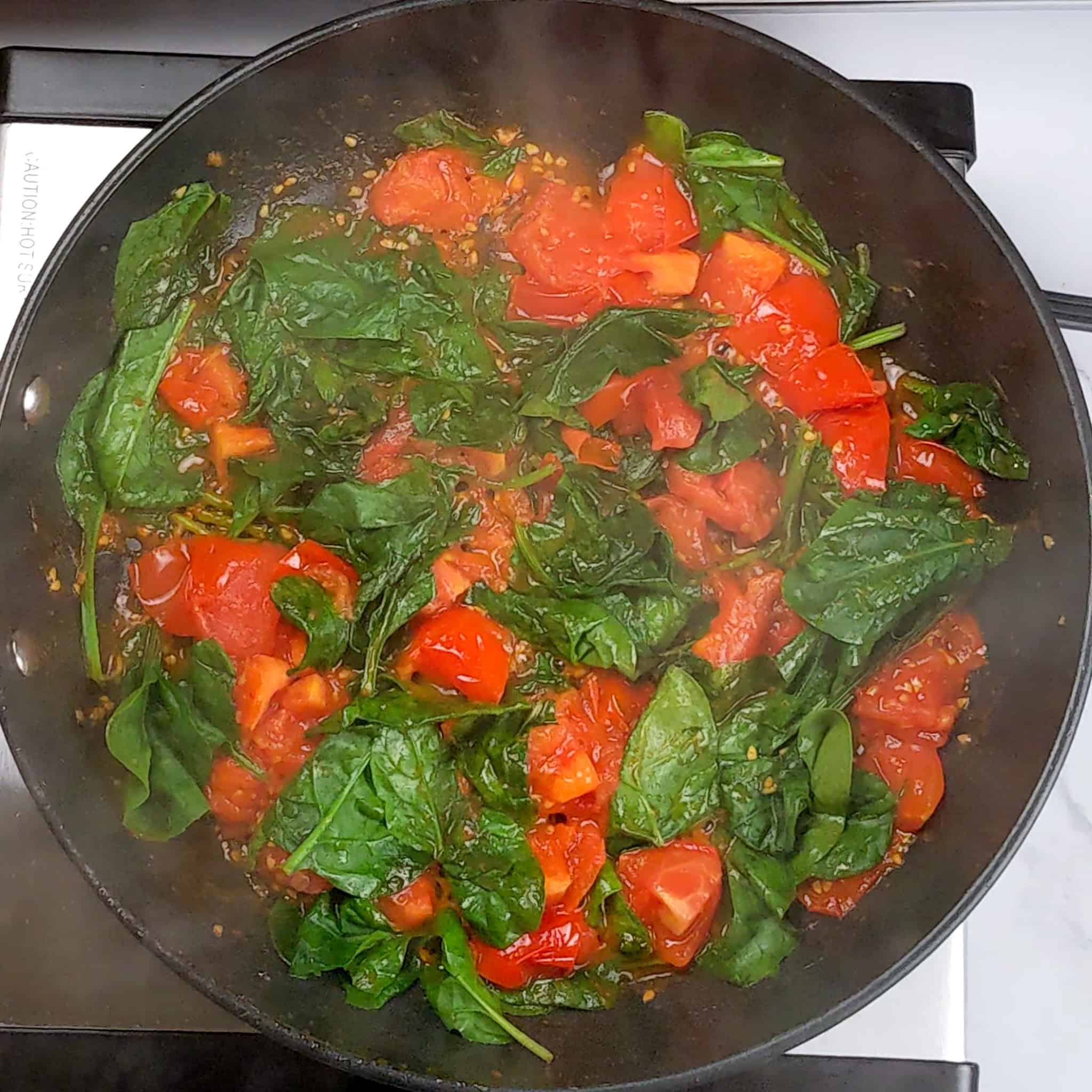 cooked quartered Campari tomatoes with wilted spinach in a non-stick all-clad skillet.