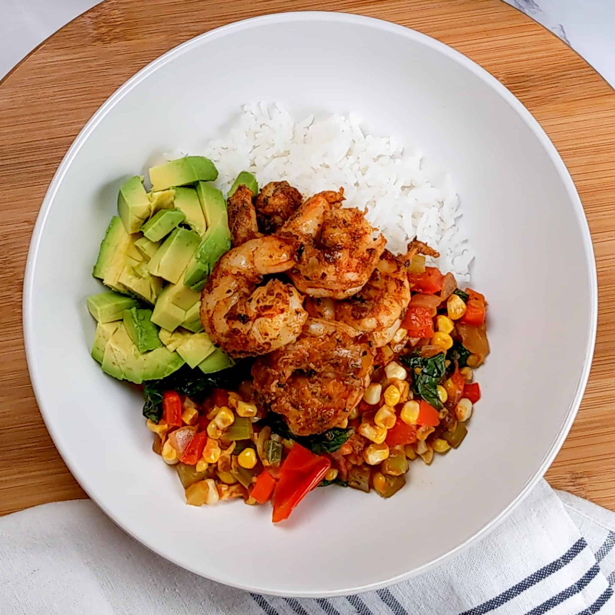 the cajun shrimp added to the top and middle of the wide rim bowl of jasmine rice, vegetable medley and diced avocados.