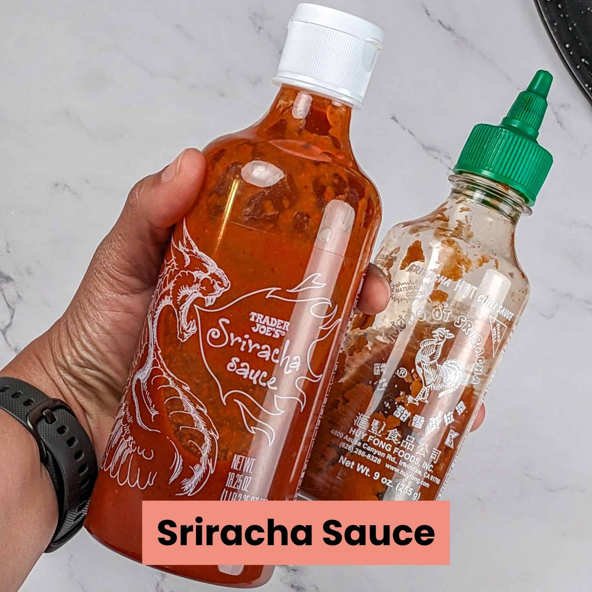 two types of sriracha sauce held in the hand, left one is Trader Joe's and the right one is Huy Fong's.