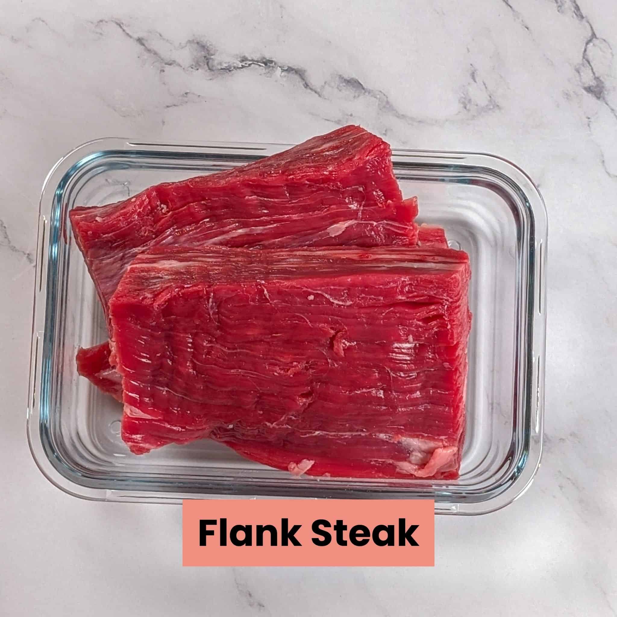 trimmed flank steak in a rectangle glass container.