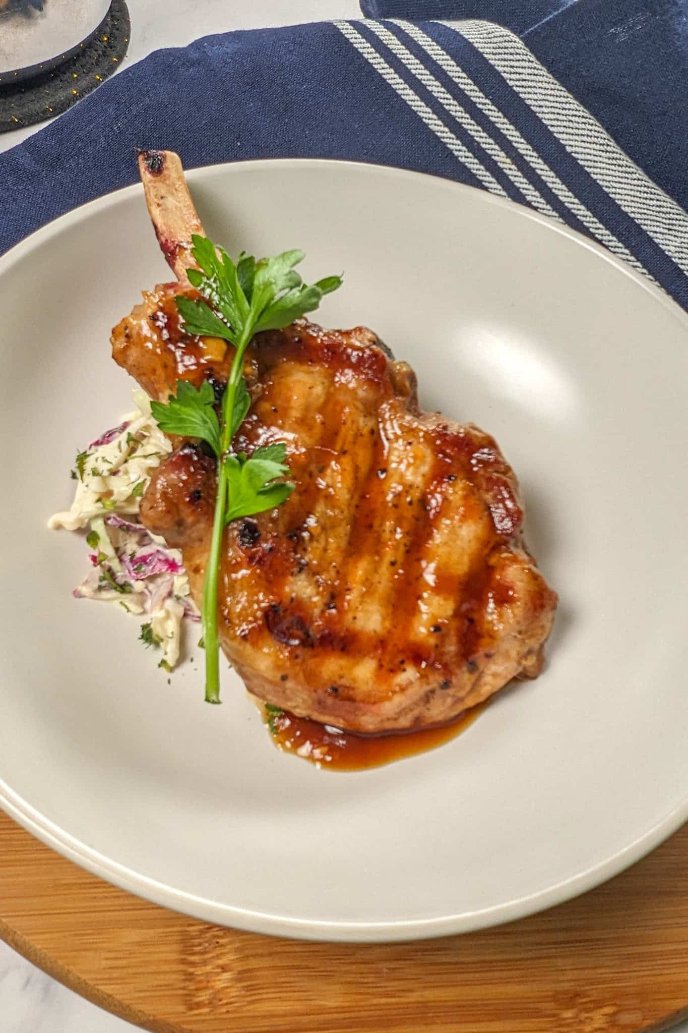 habanero tamarind glazed pork chop on a bed of deli-style coleslaw on a wide rim bowl.