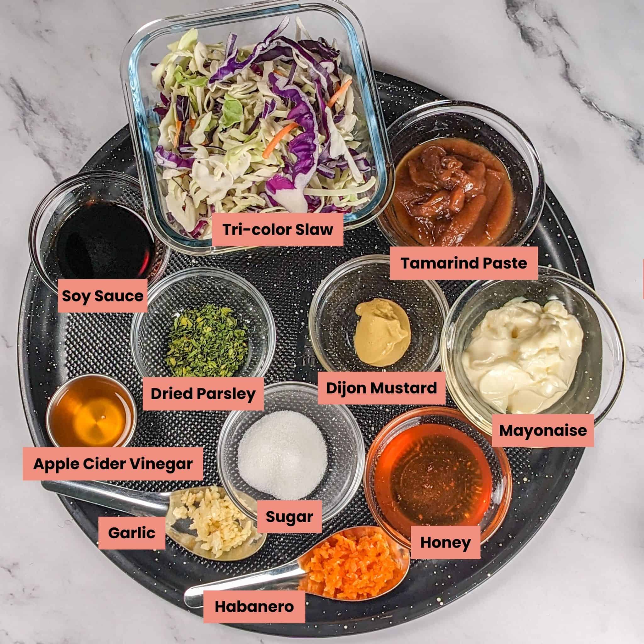 Ingredients for the Grilled Pork Chops with Tamarind Habanero Glaze and Coleslaw in containers on a large round pizza pan.