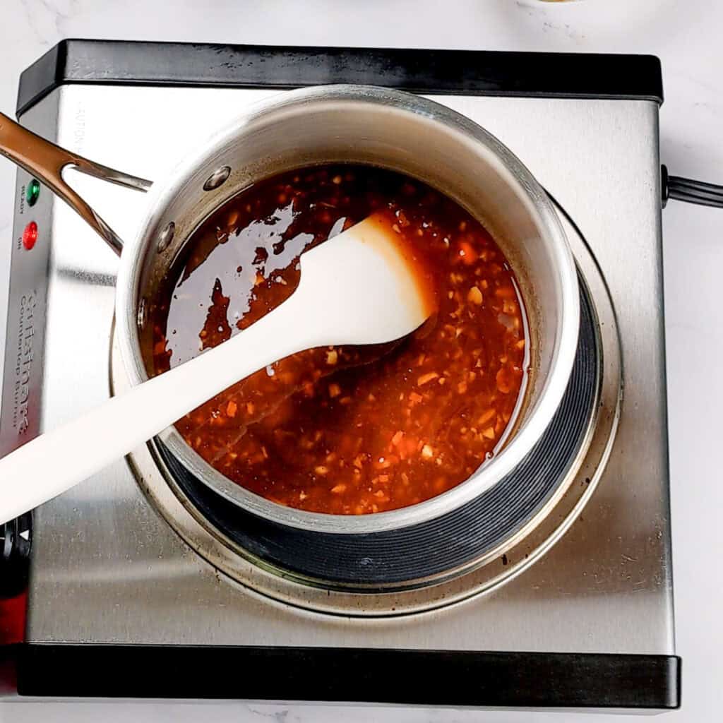 ingredients for the tamarind habanero glaze in a sauce pot with a silicon rubber spatula.