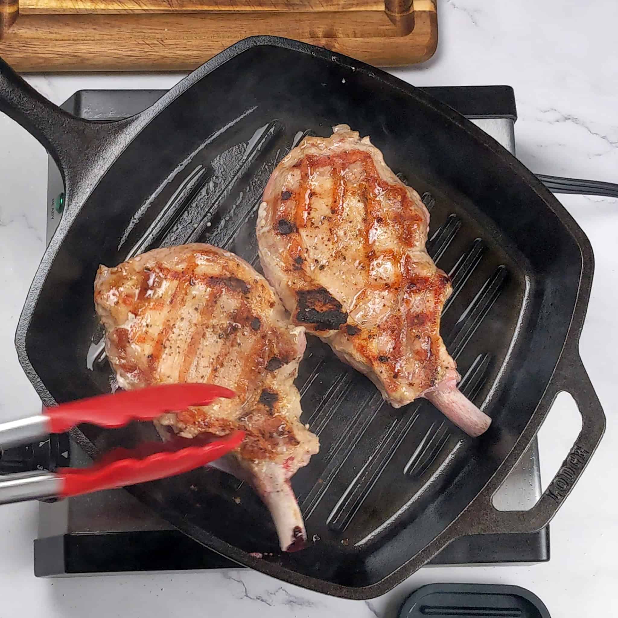 diamond grill marked pork chops in a grill pan.