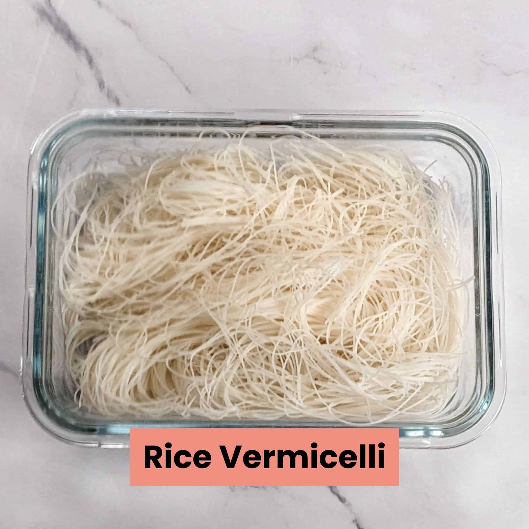 soaked and drained rice vermicelli noodles in a rectangle glass container.