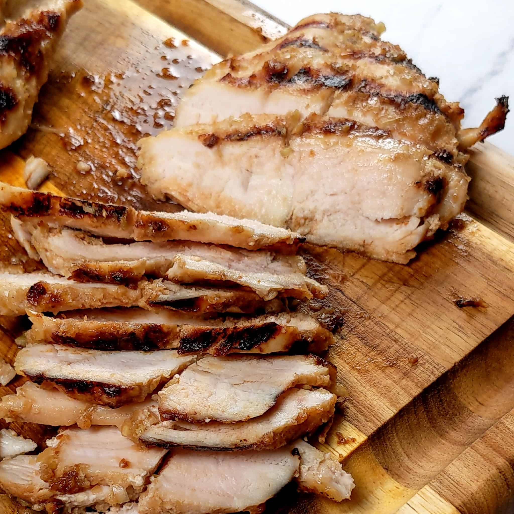 sliced grilled marinated lemongrass chicken on a cutting board.