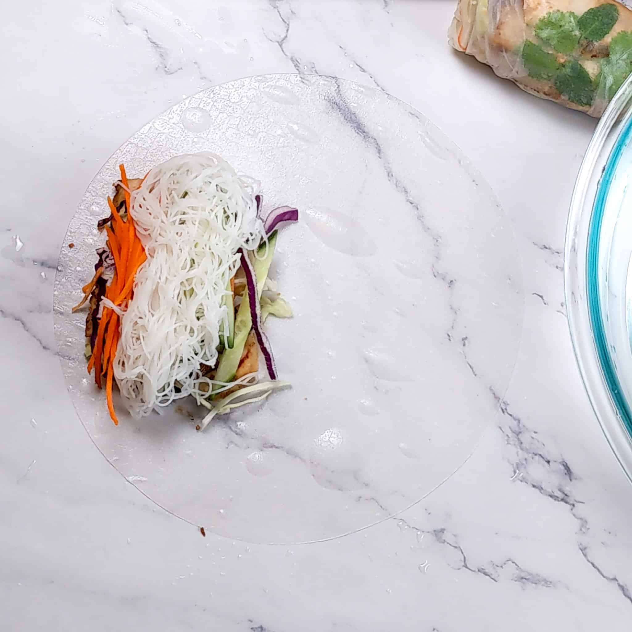 stacked ingredients on one side of the rice paper roll.