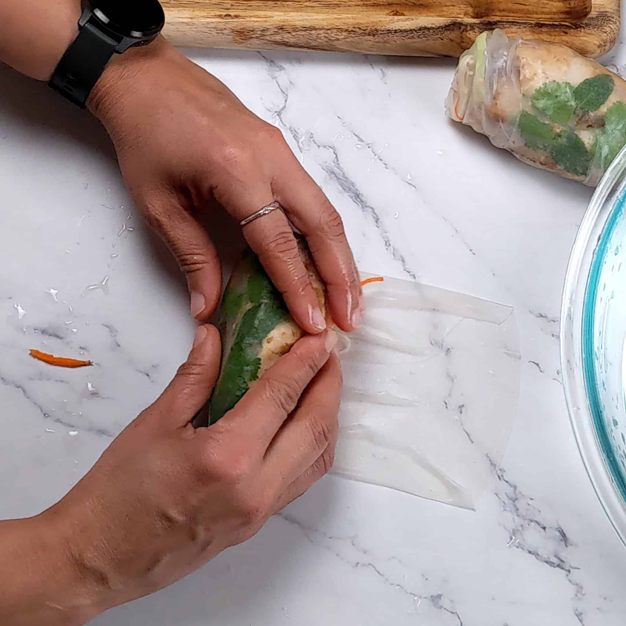 the lemongrass marinated chicken spring roll half rolled up by two hands.