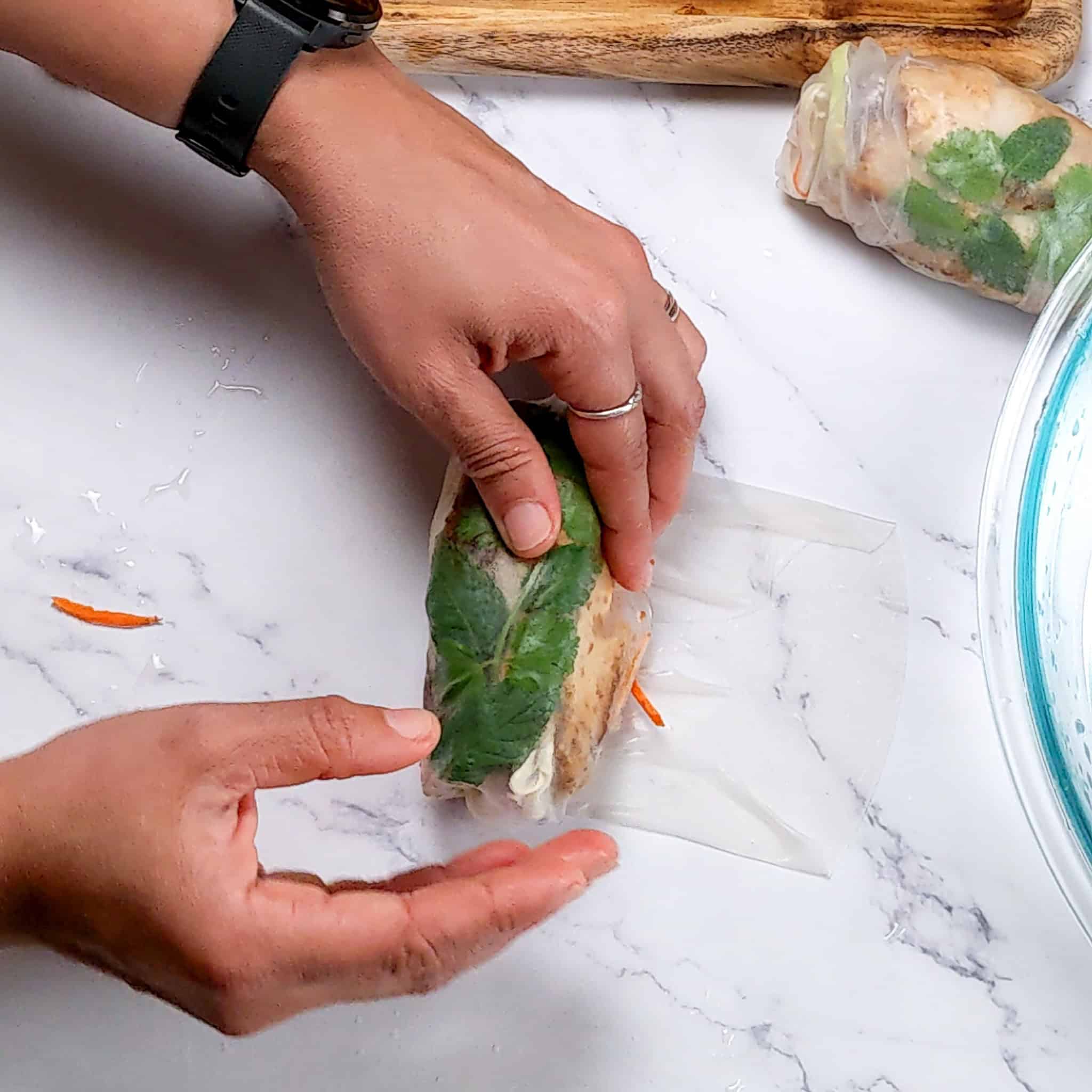 the lemongrass marinated chicken spring roll half rolled up with one hand.