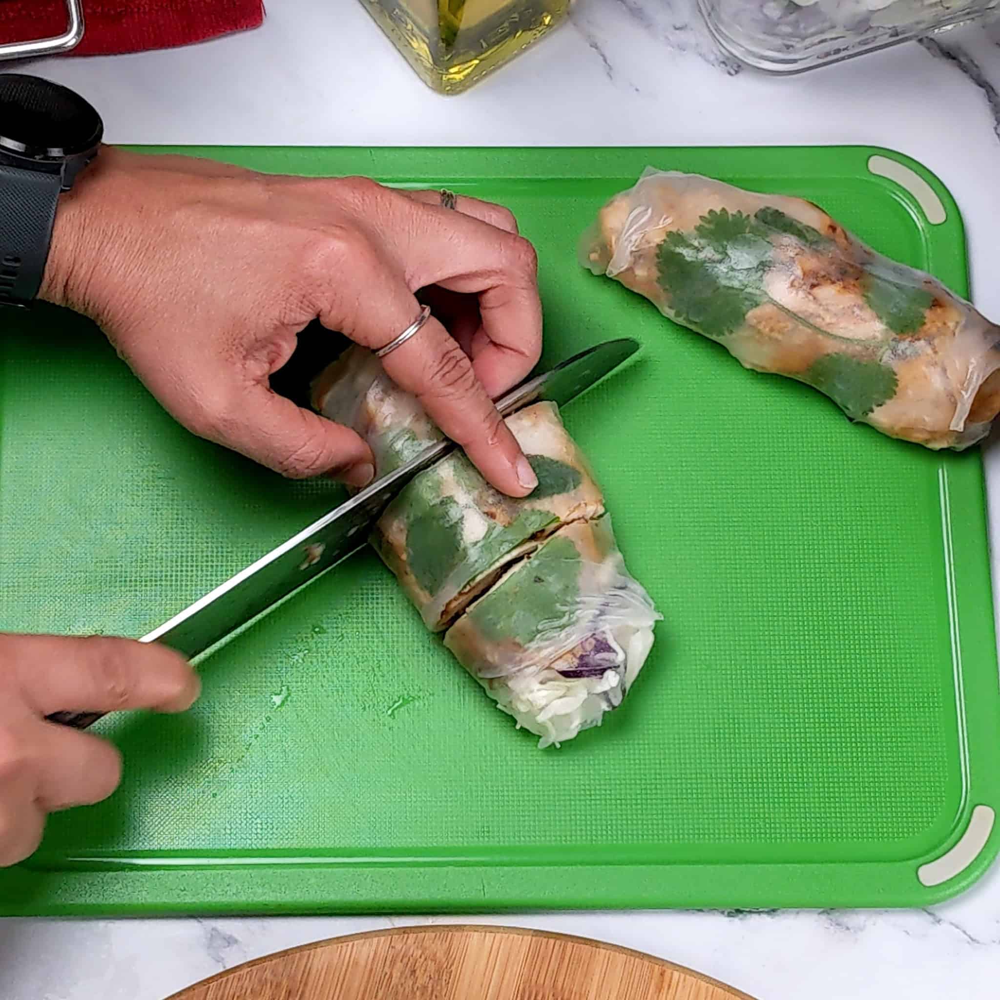 The lemongrass marinated spring roll being sliced into thirds on a color coded cutting board for ready to eat foods.