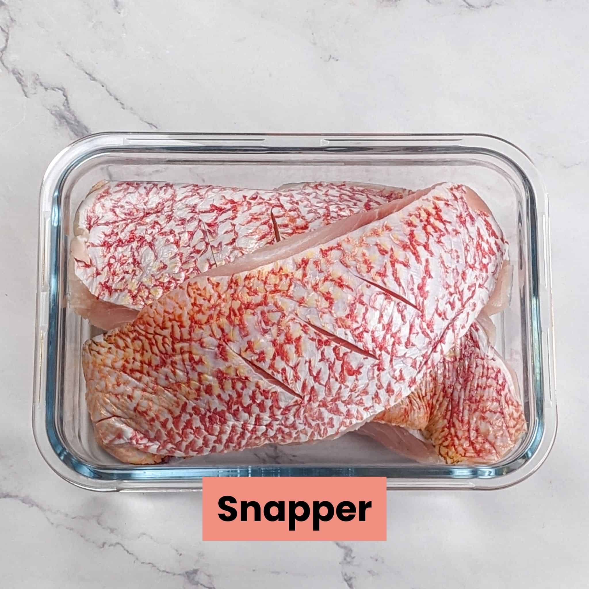 red snapper filets in a rectangle glass container.