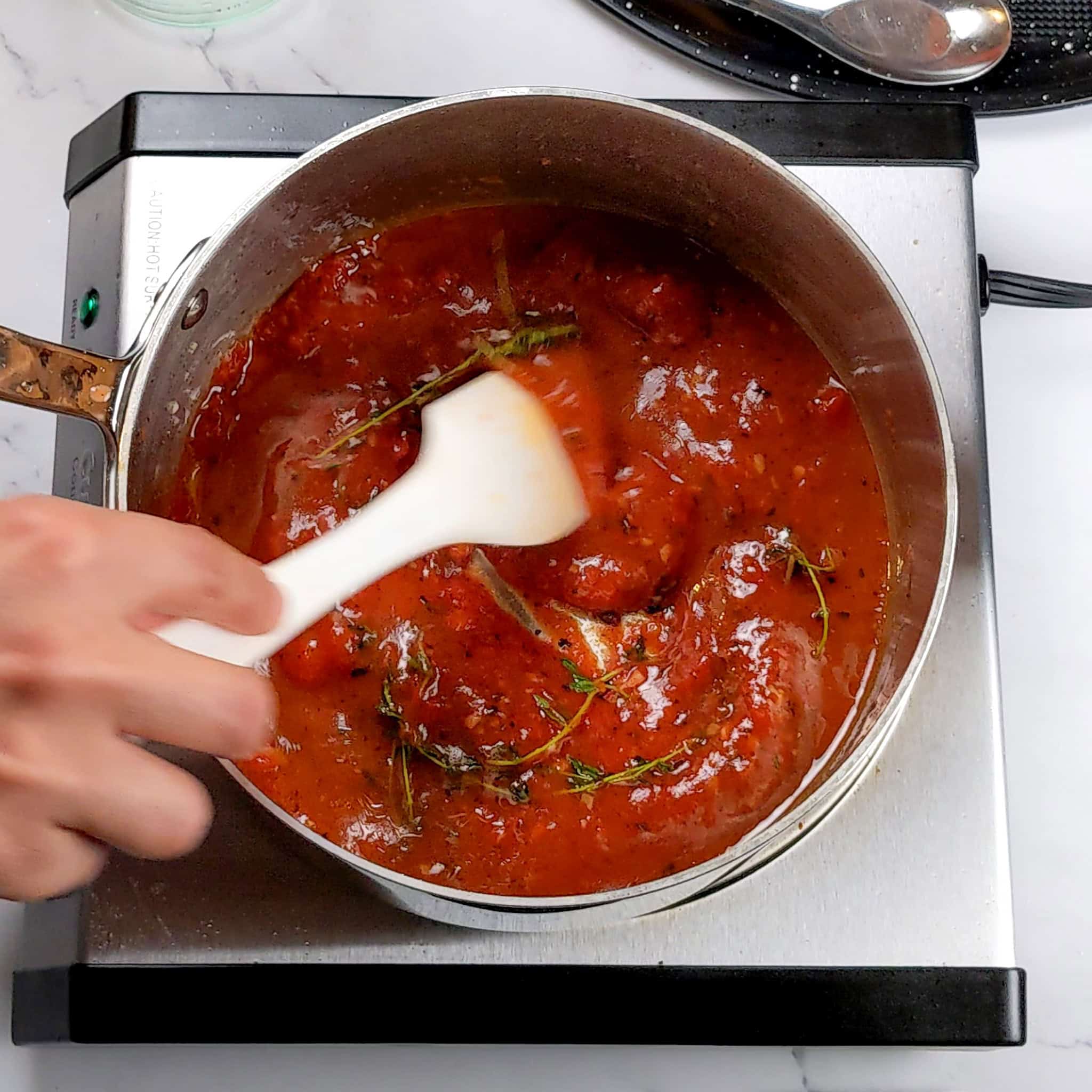 spicy creole sauce mixed with a silicone spatula in a sauce pot.