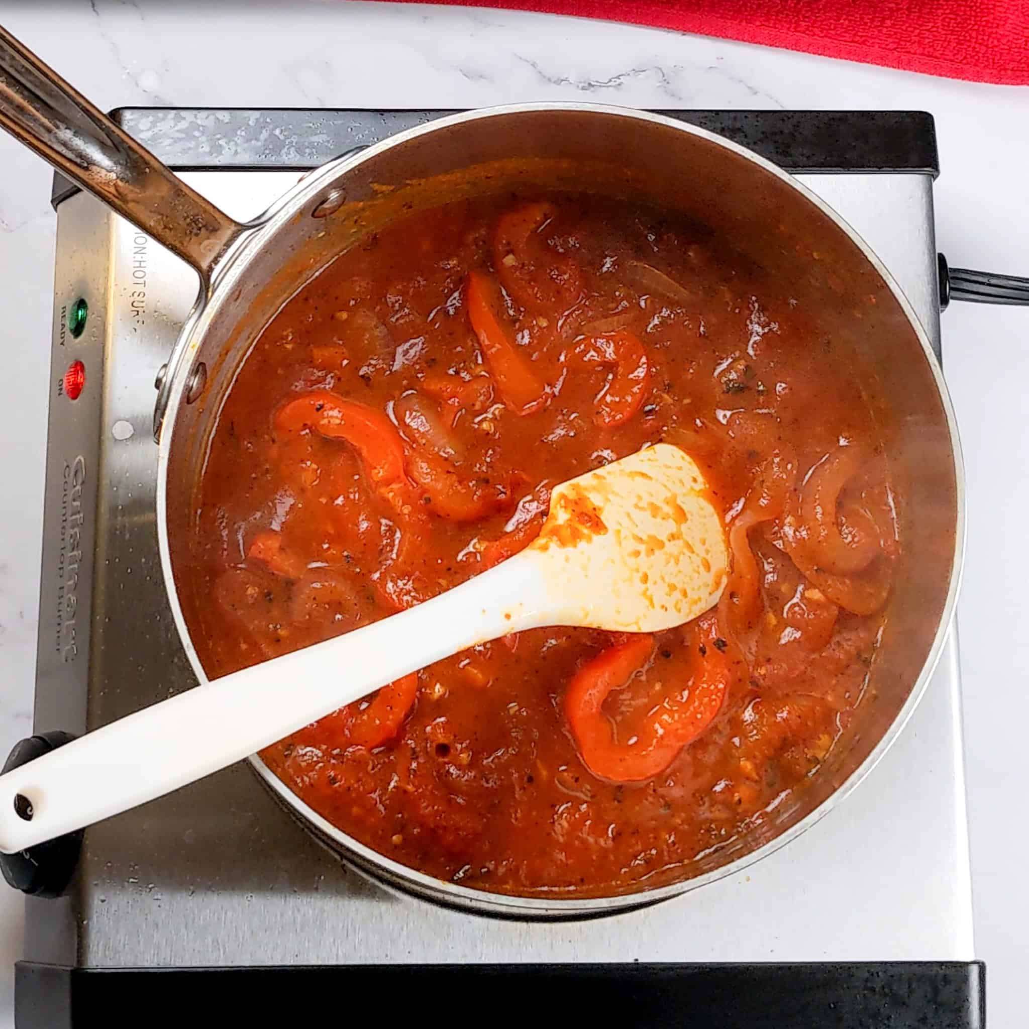 spicy creole sauce in a sauce pot with a silicone spatula.