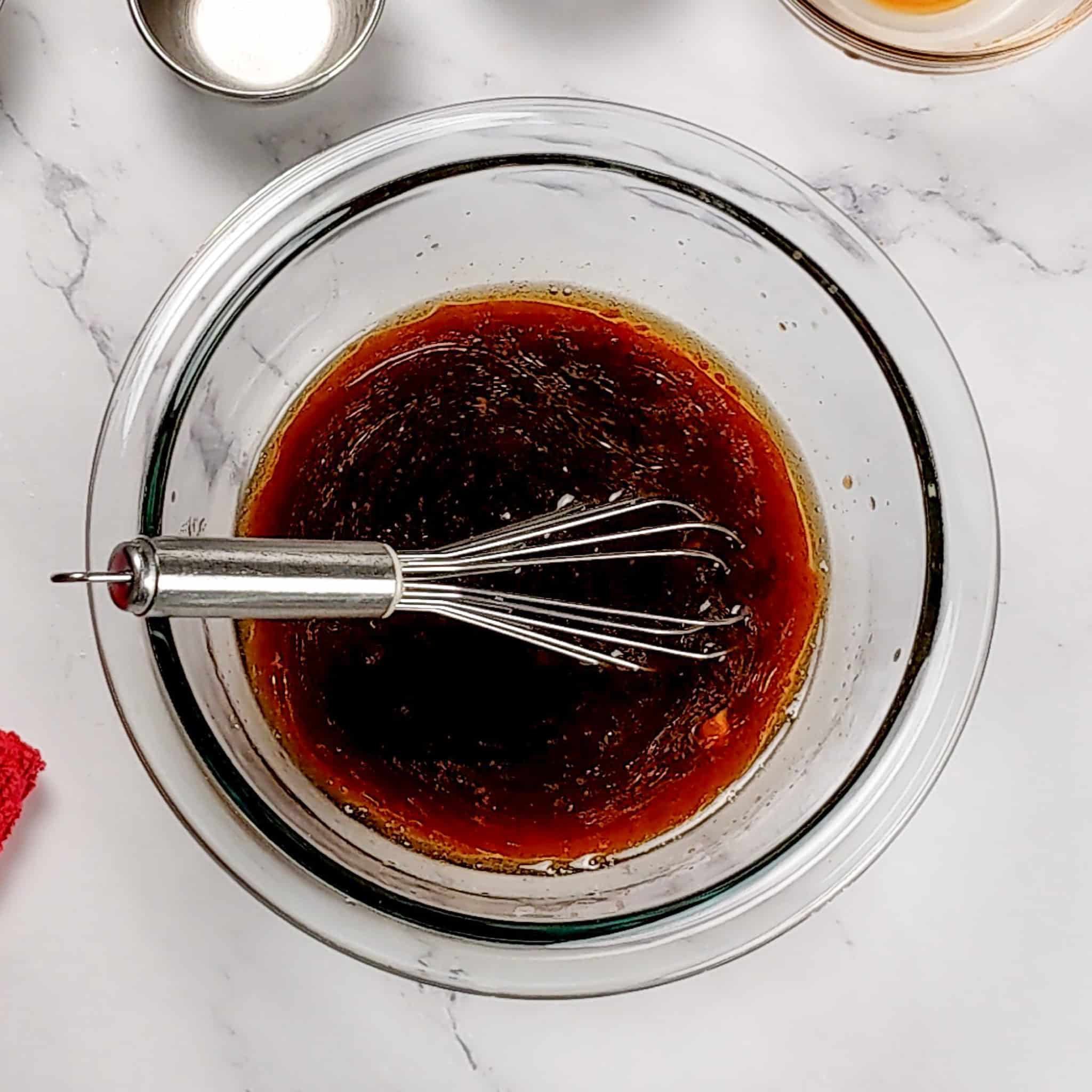 soy-sesame dressing in a glass mixing bowl with a mini whisk.