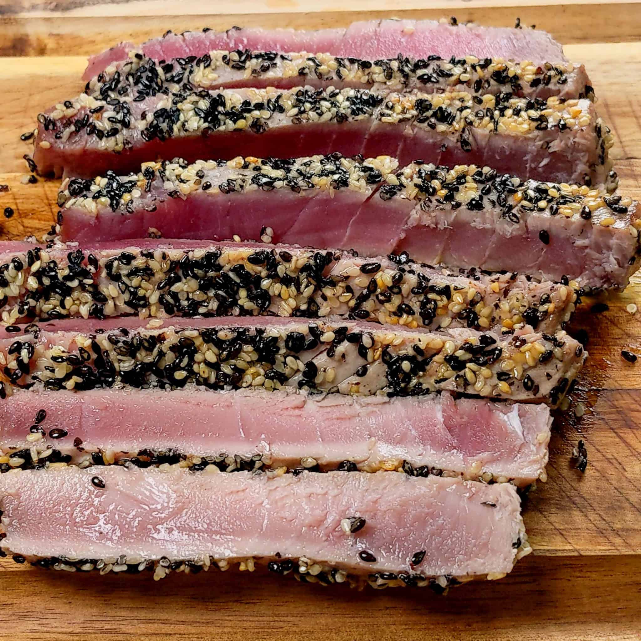 sesame seed crusted ahi tuna sliced on a wooden cutting board.