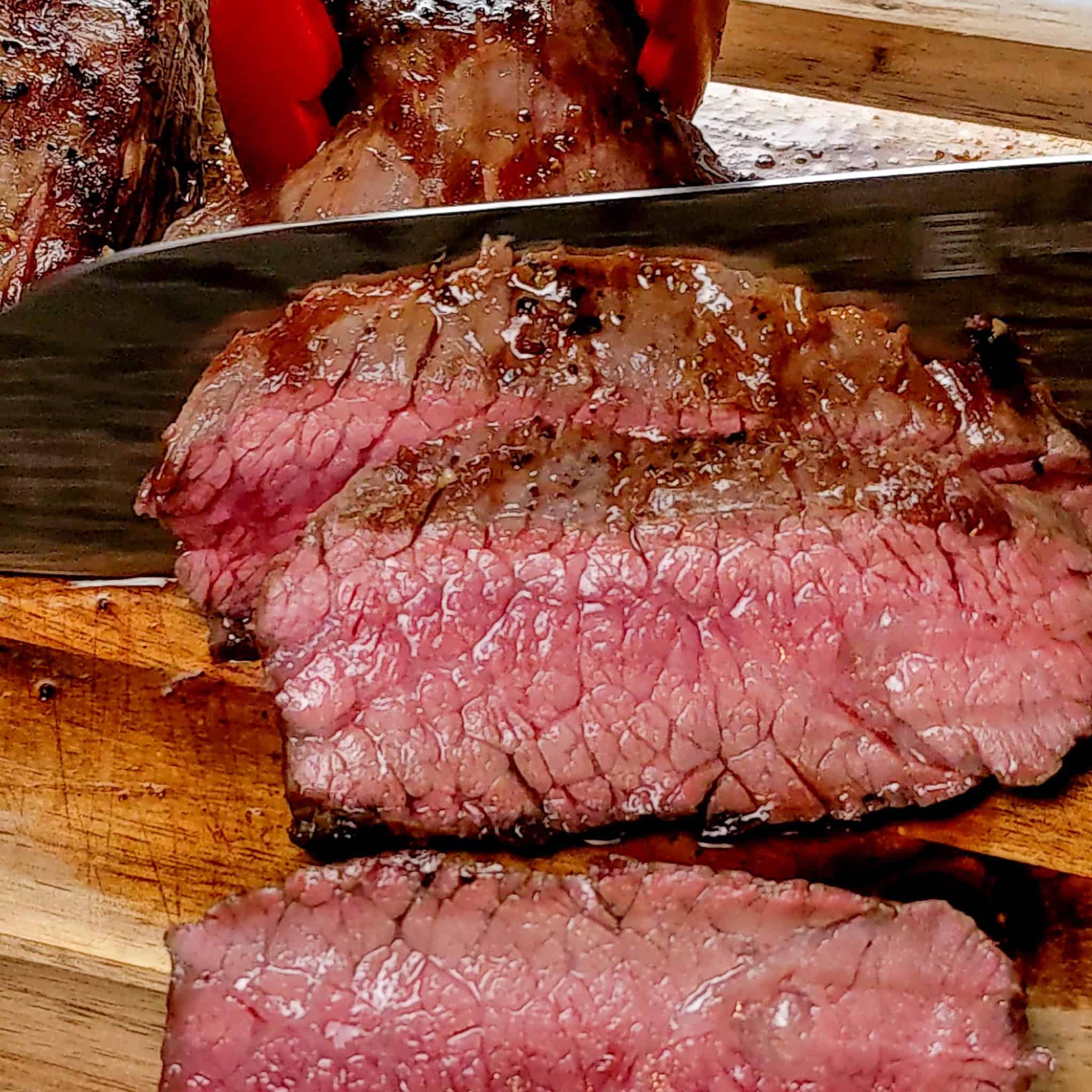 pan-grilled flank steak being thinly sliced.