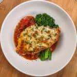 Baked Cheesy Spicy Tomato Basil Chicken and Broccolini on a wide rim bowl.