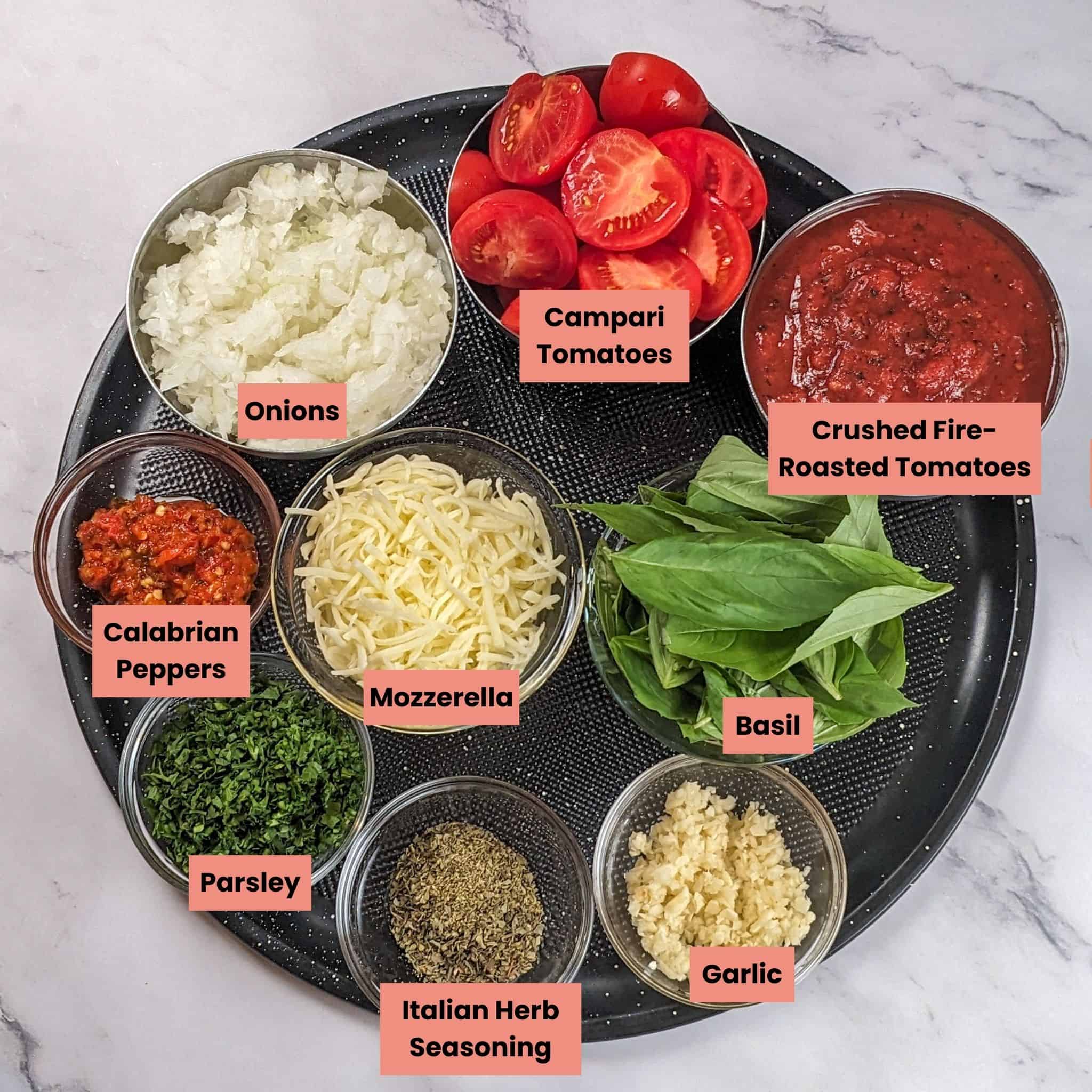 ingredients for the Baked Chicken with Mozzarella in Spicy Tomato Basil Sauce in containers on a large round pizza pan.