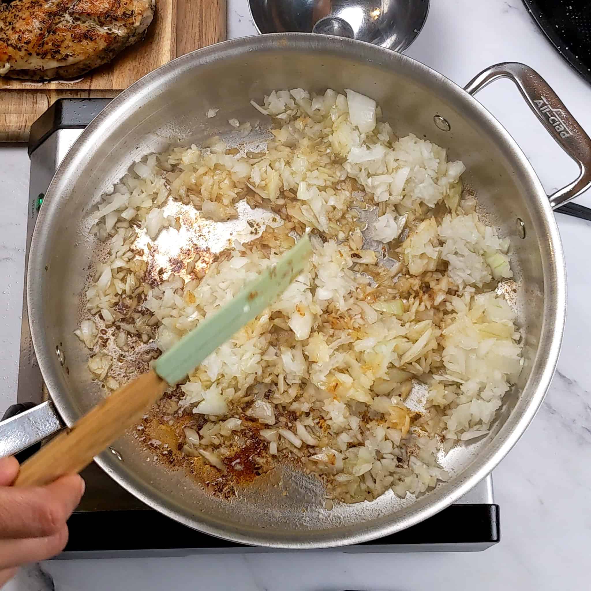 chopped onion being browned in an all-clad saute pan.