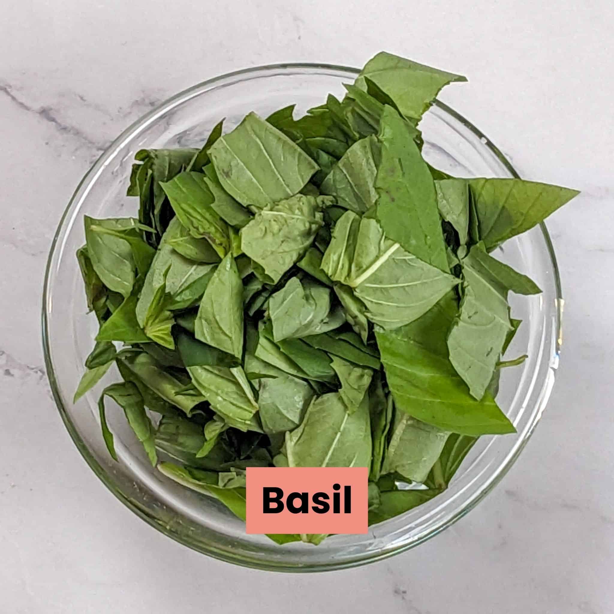 torn basil leaves in a small round glass dish.