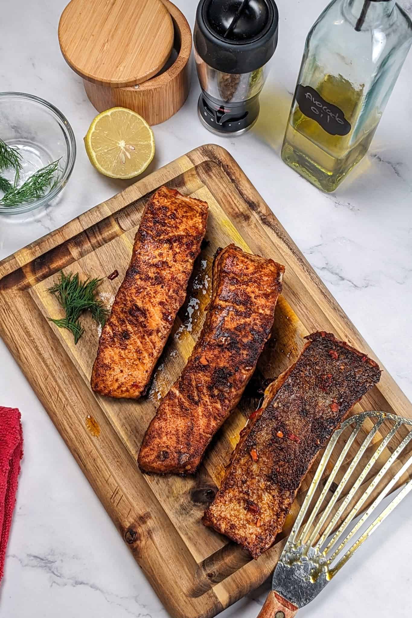 pan seared smoked paprika calabrian pepper marinated salmon on a cutting board next to a fish spatula.