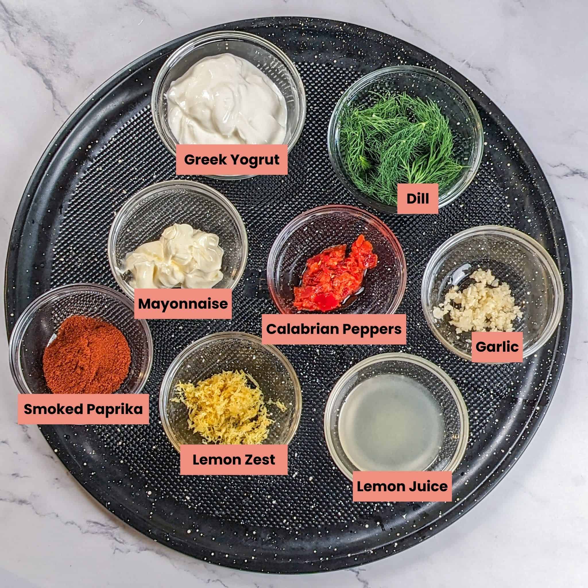 Ingredients for the Calabrian Pepper Salmon with Creamy Lemon Dill Sauce in containers on a pizza pan.