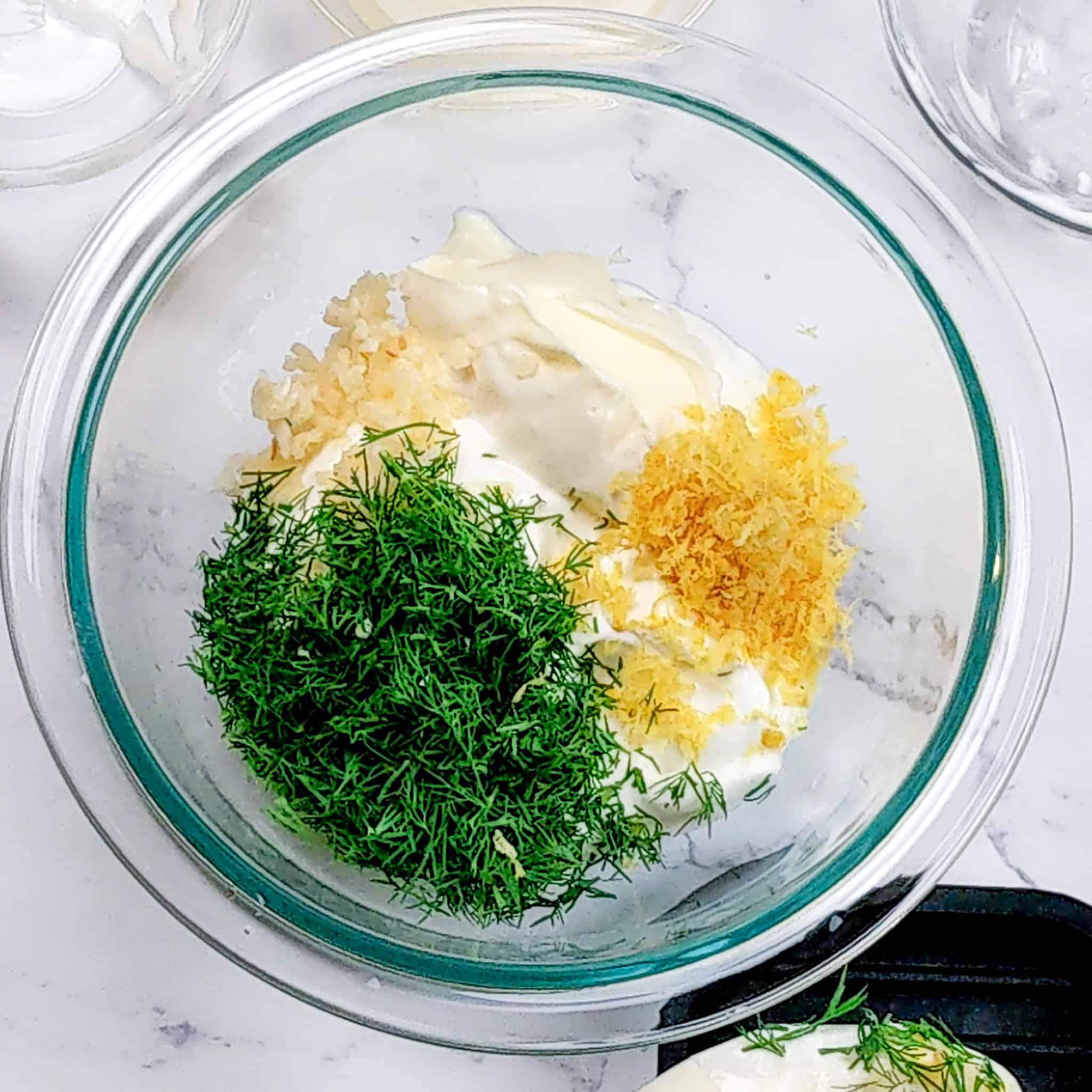 ingredients for the lemon dill sauce in a glass pyrex mixing bowl.