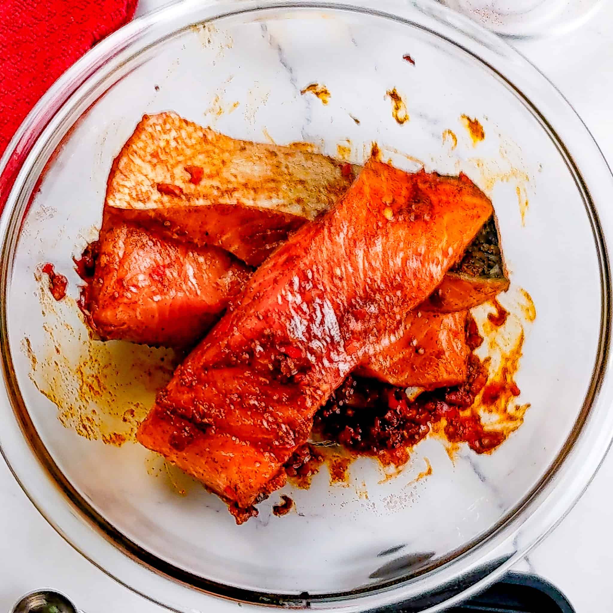 smoked paprika calabrian pepper marinated salmon filets in a glass mixing bowl.