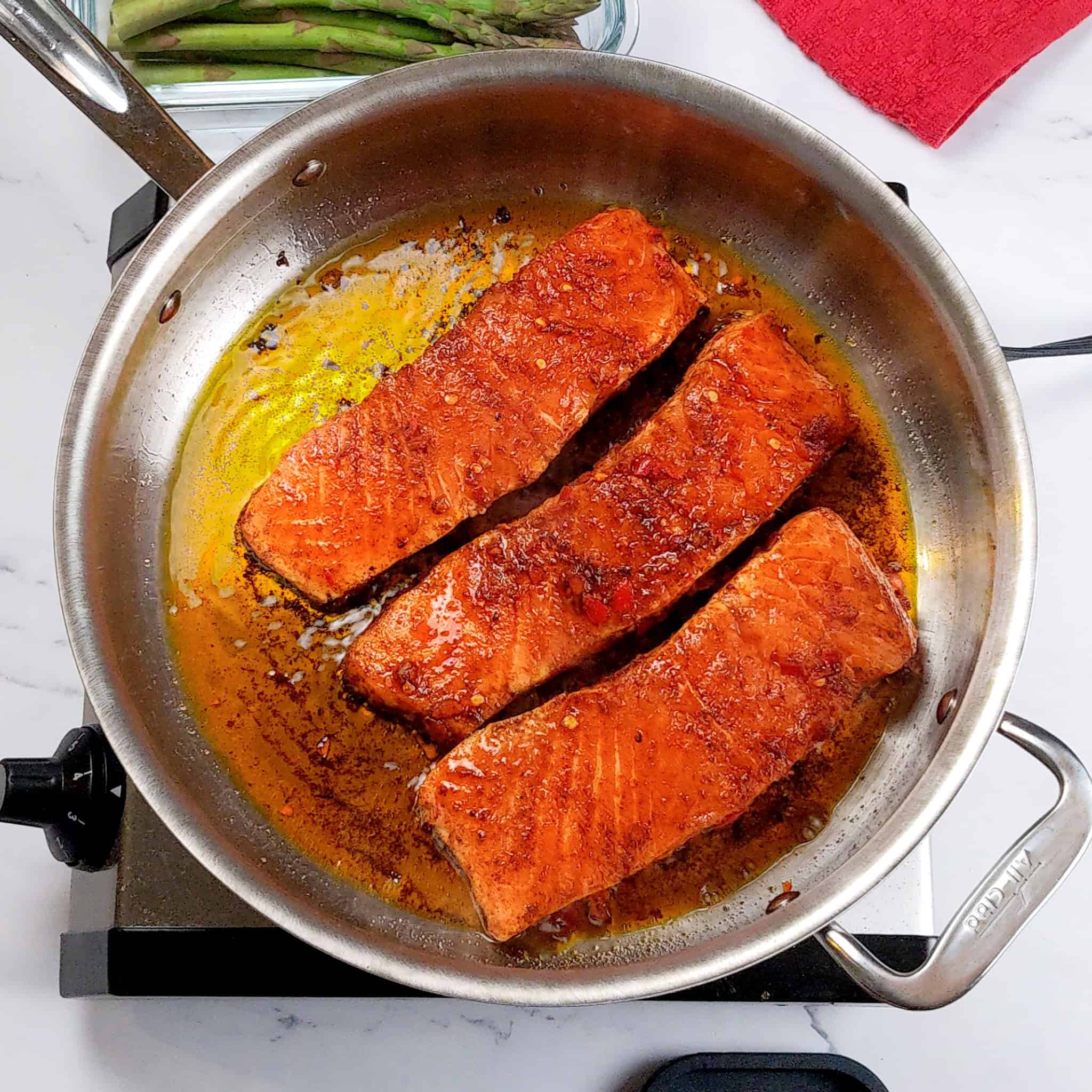 marinated salmon pan searing in a large saute pan.