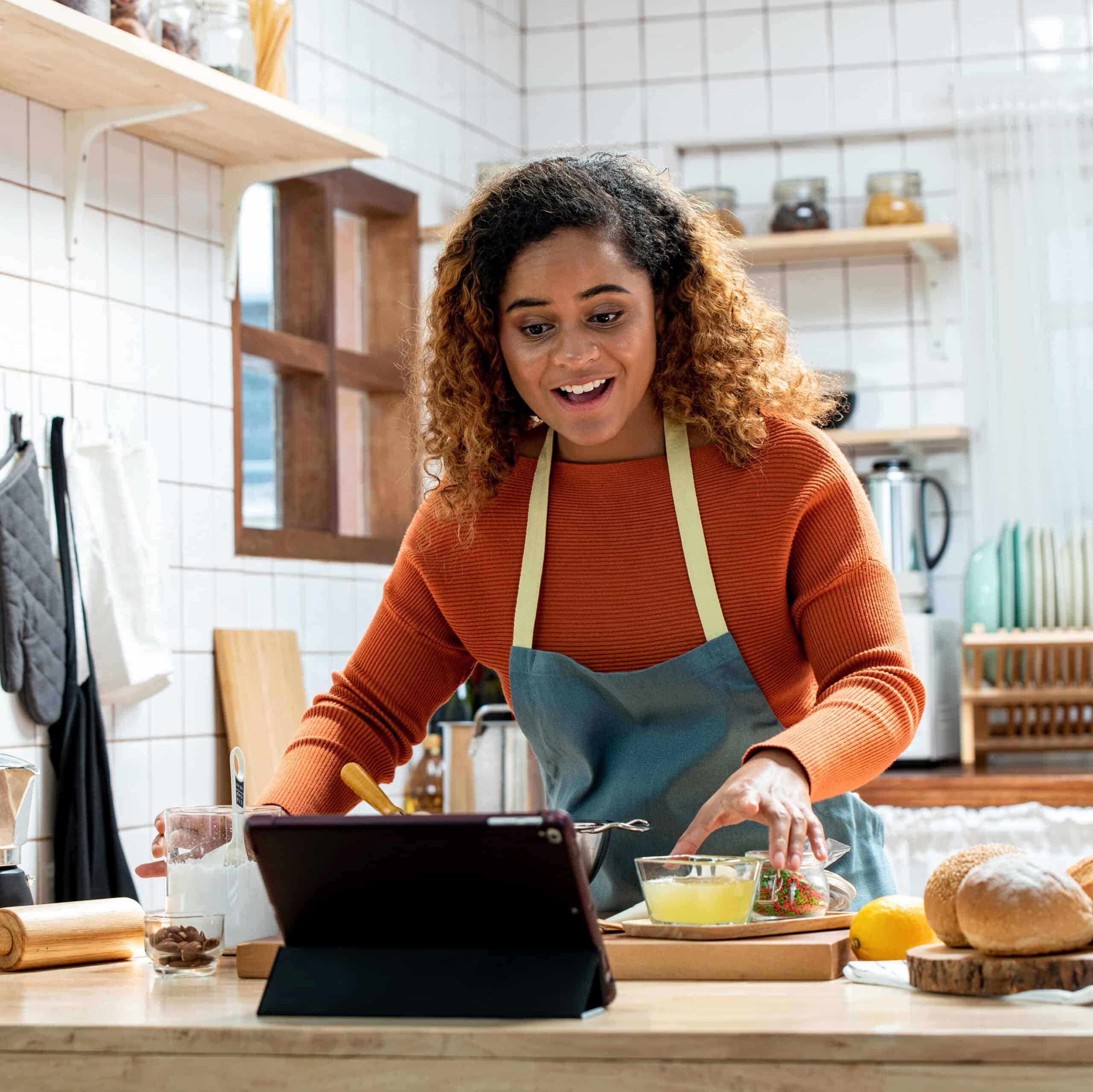 Young Afican American woman learning online  cooking class via tablet computer in kitchen at home