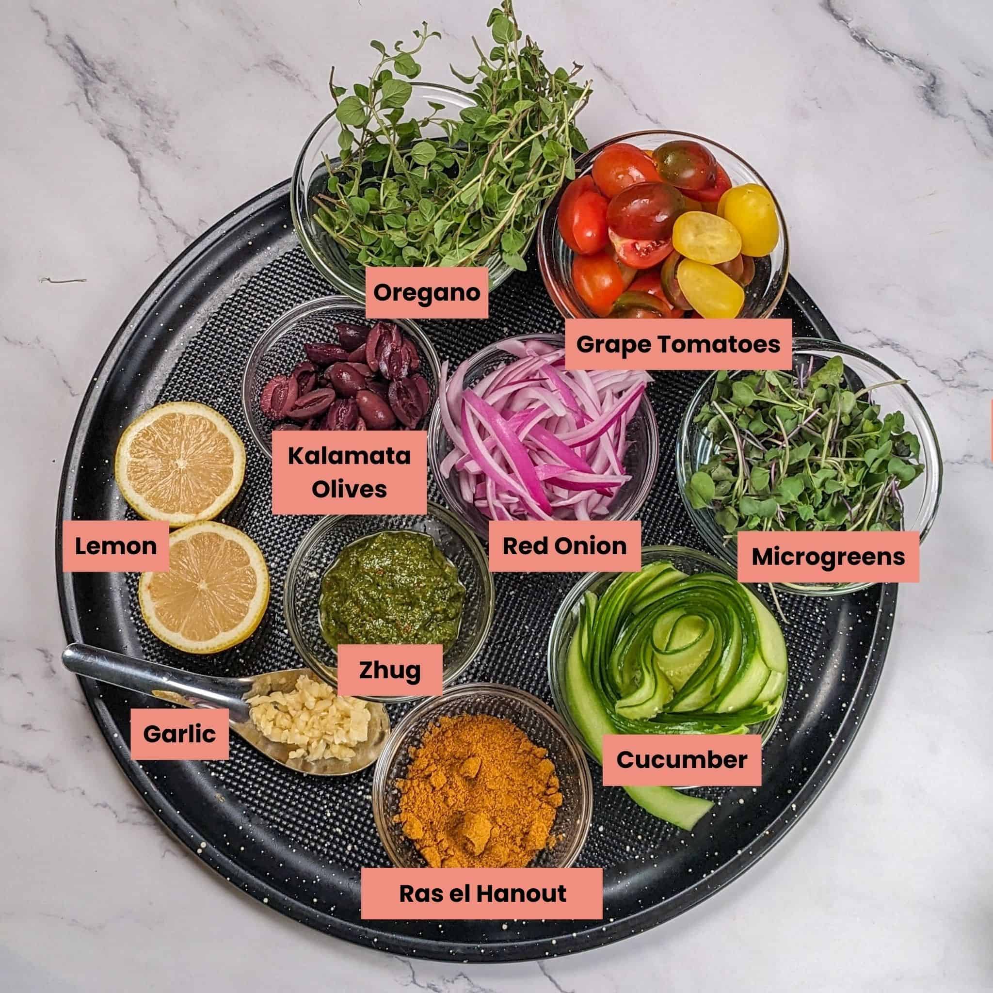 ingredients for the Grilled Zhug Ras el Hanout Lamb Chops and Tomato Salad in dishes on a large round pizza pan.