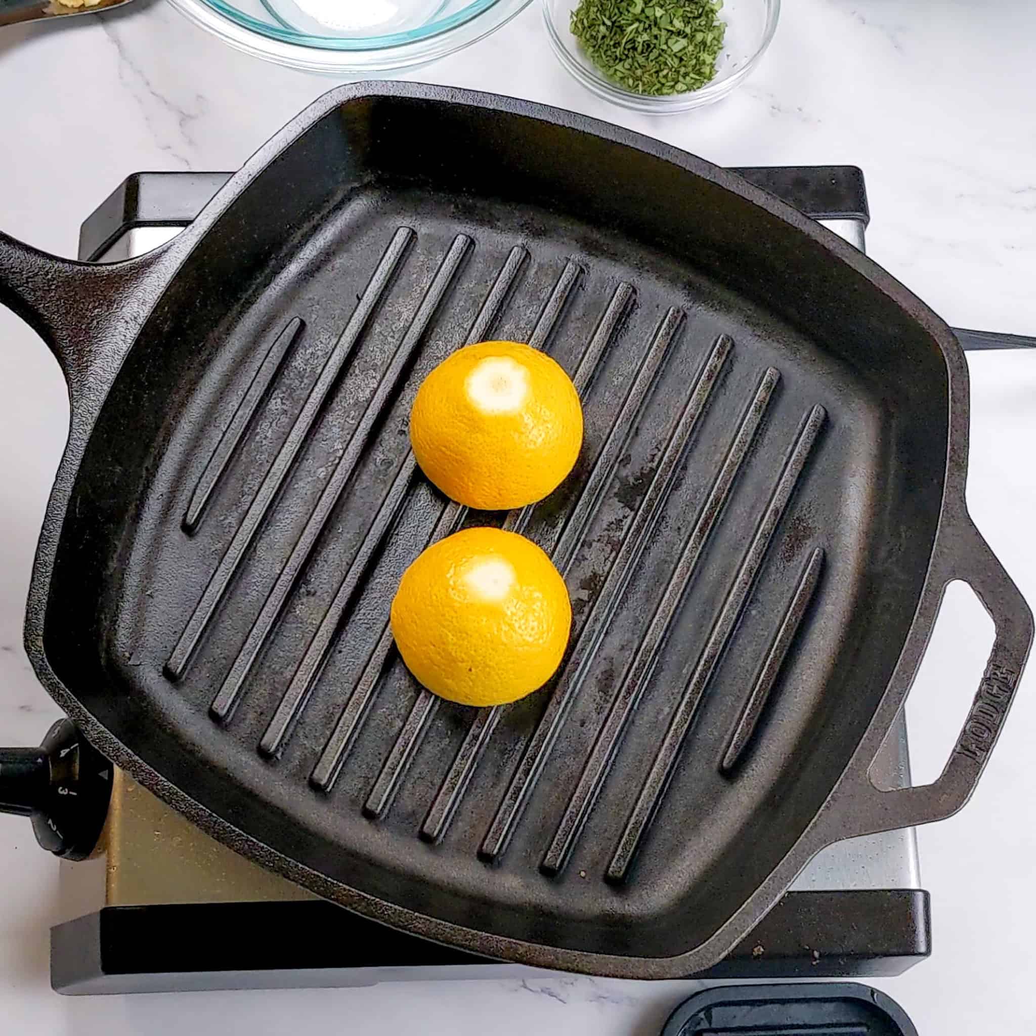 lemons being grilled cut side down in a lodge cast iron grill pan.