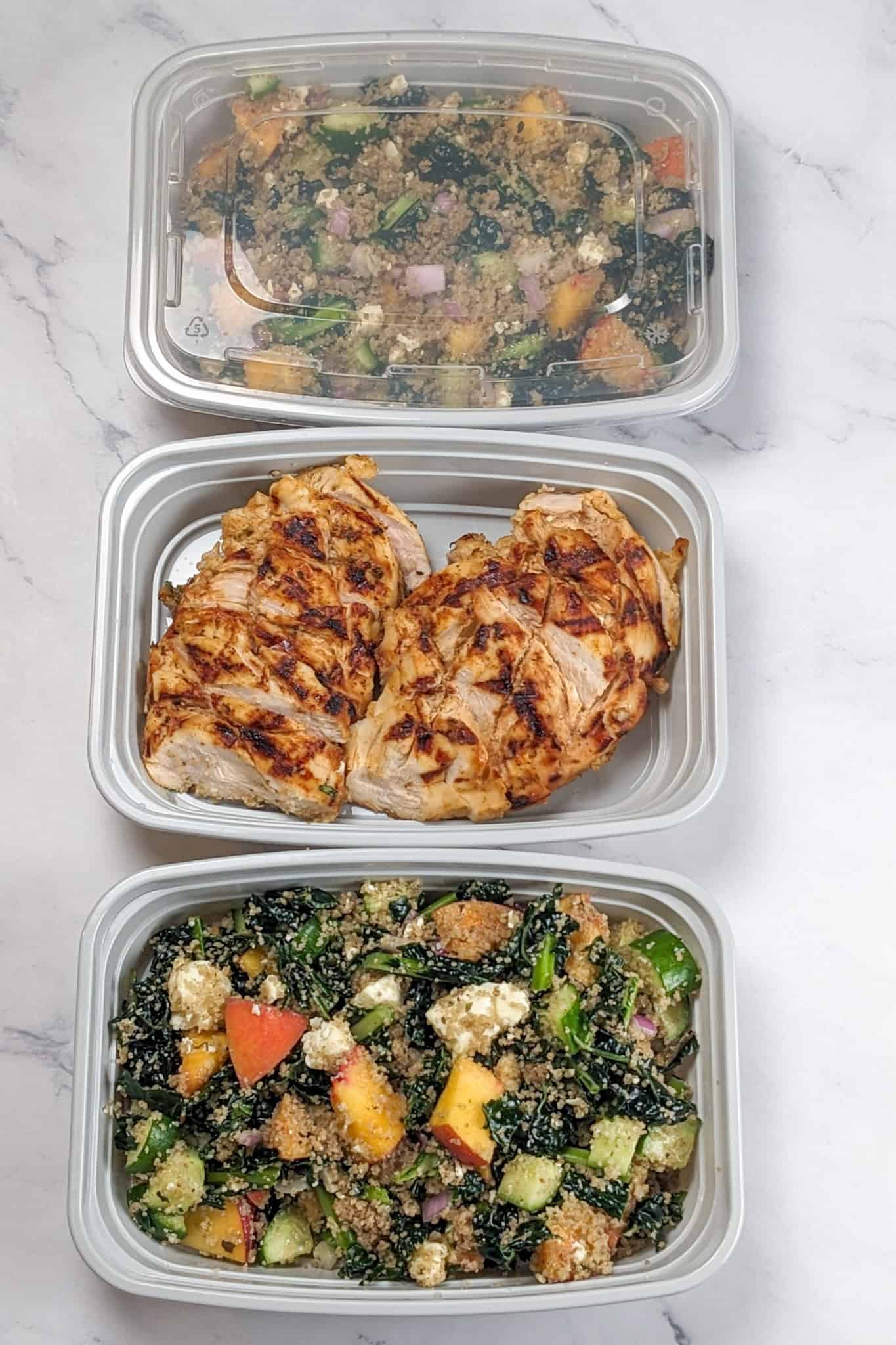 The Peach Piri Piri Chicken with Fonio Kale Salad meal in meal prep containers with the chicken and salad separated.