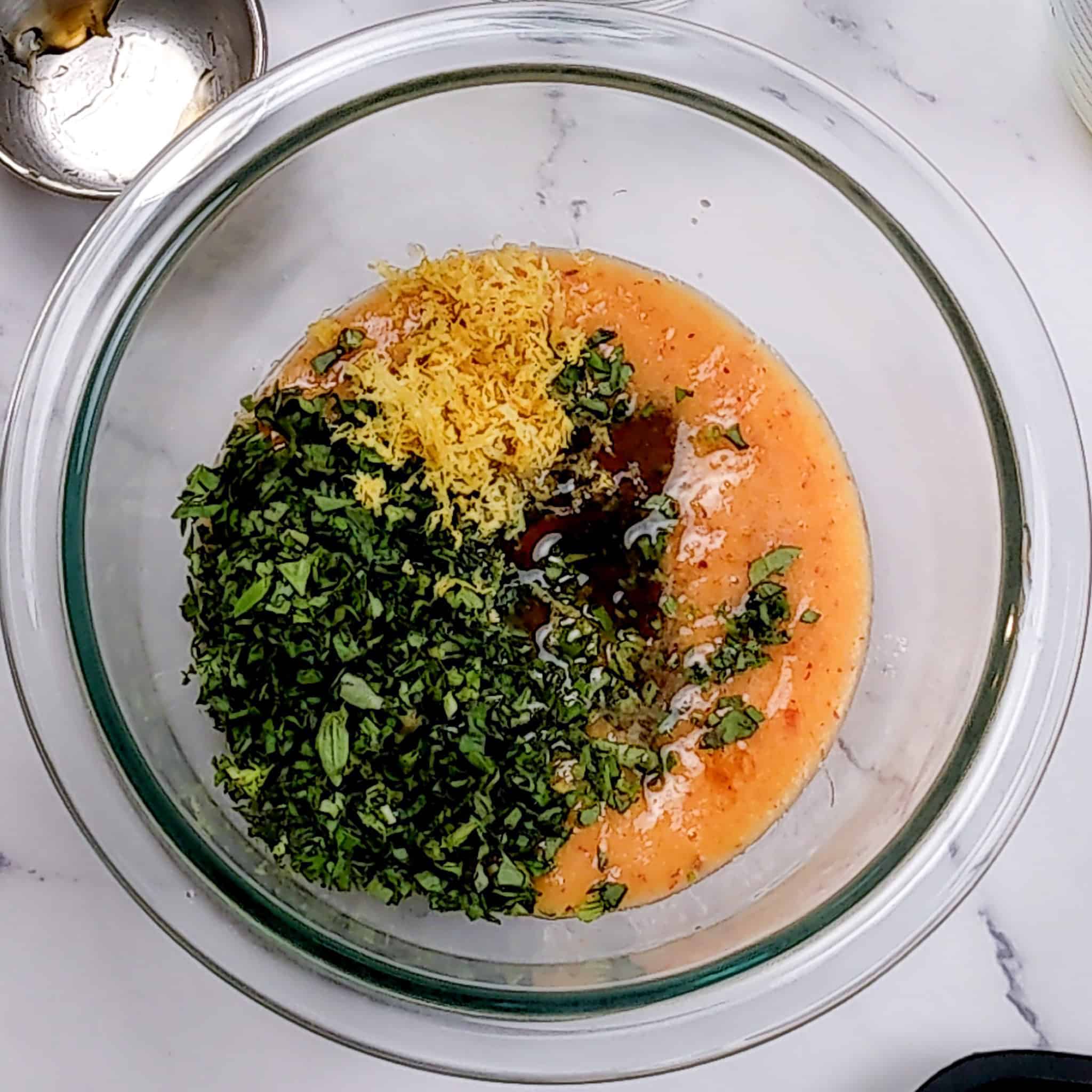 ingredients for the peach vinaigrette in a pyrex glass mixing bowl.