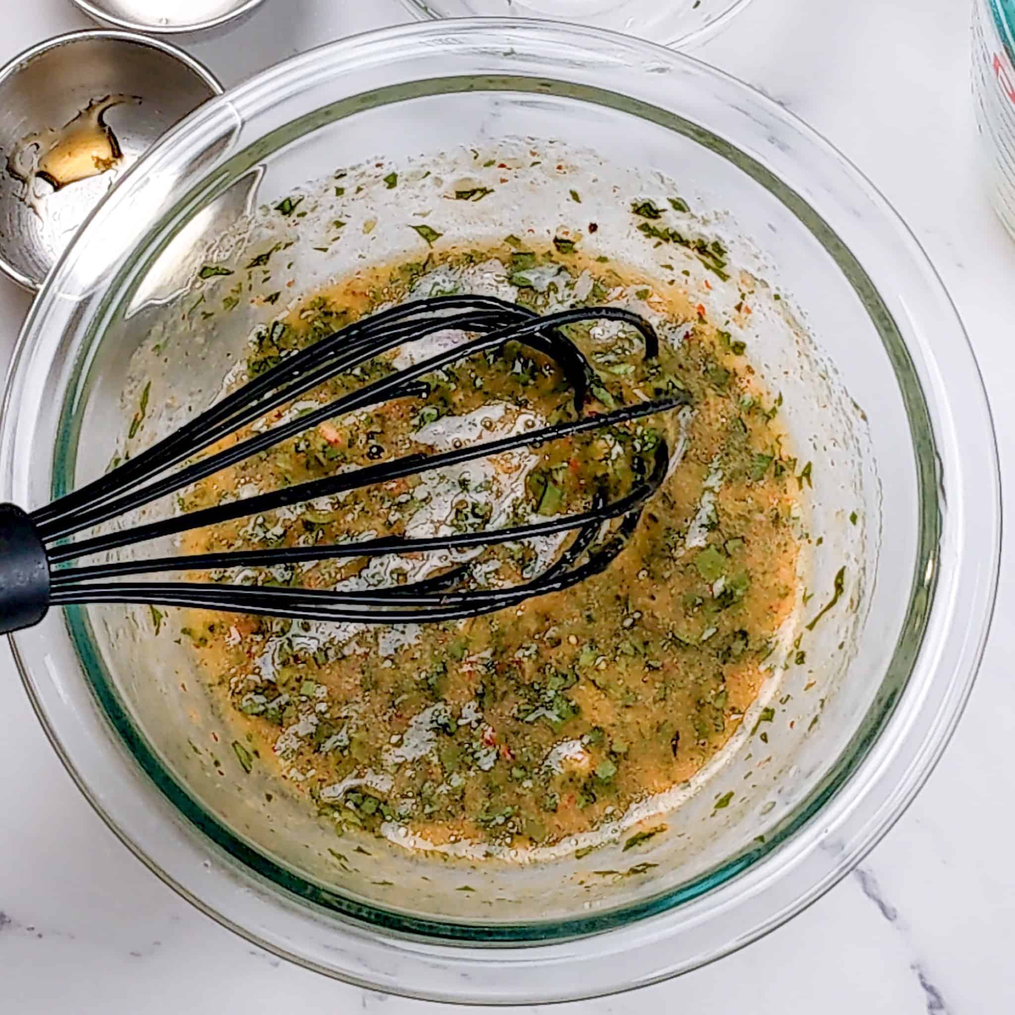 the peach vinaigrette in a pyrex glass mixing bowl with a silicone whisk.