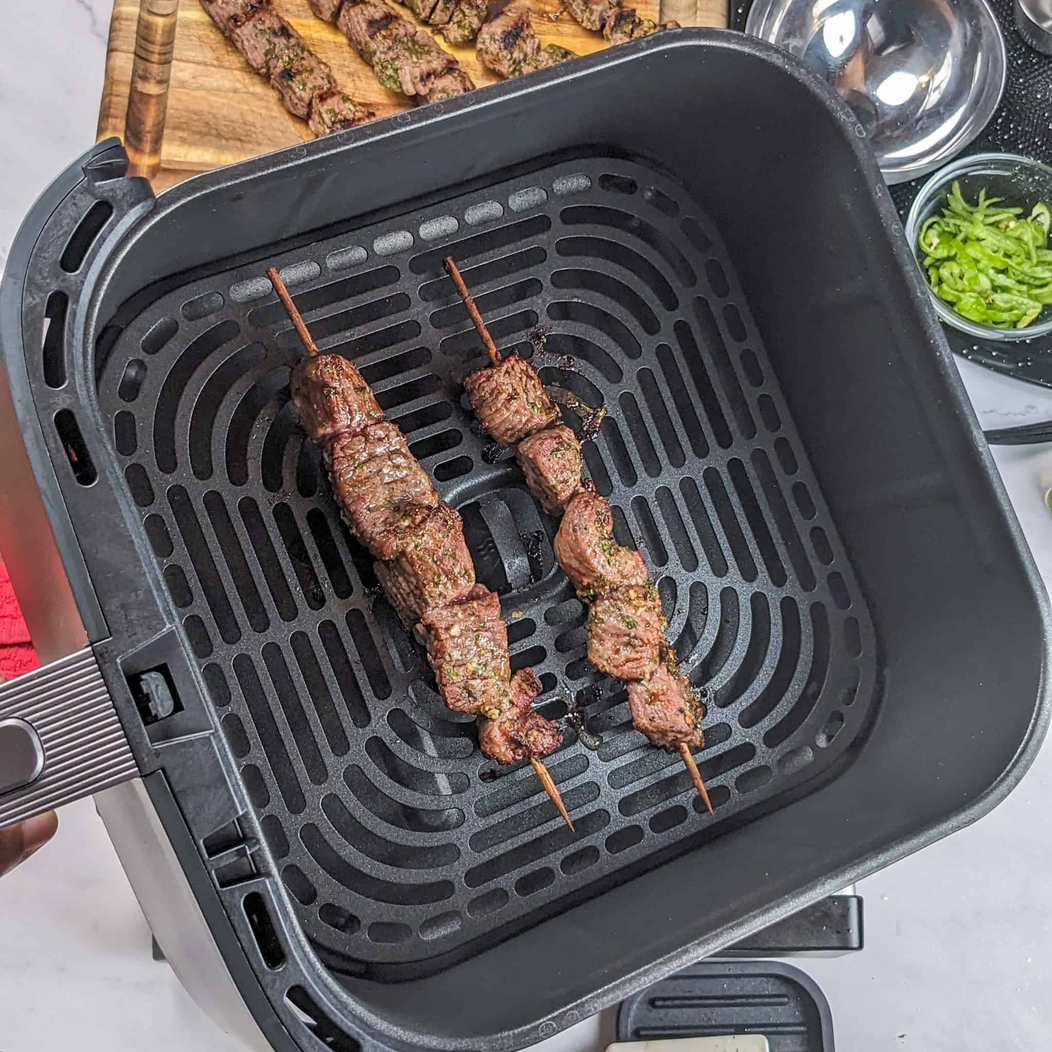 Cooked beef skewers in an air fryer basket.