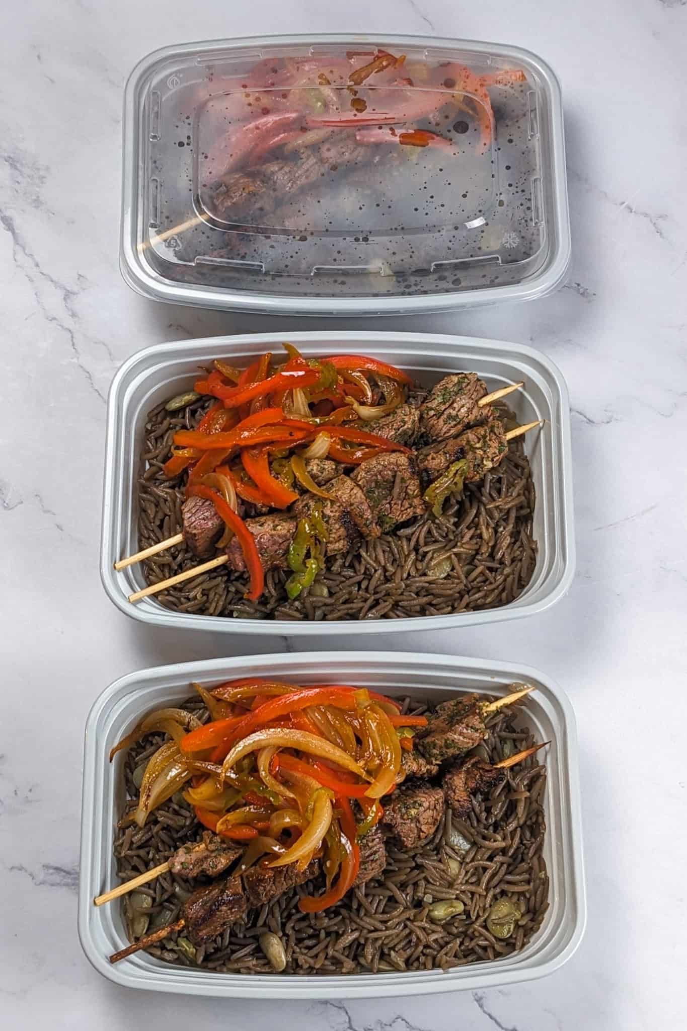 The grilled beef skewers with black mushroom rice in meal prep containers.