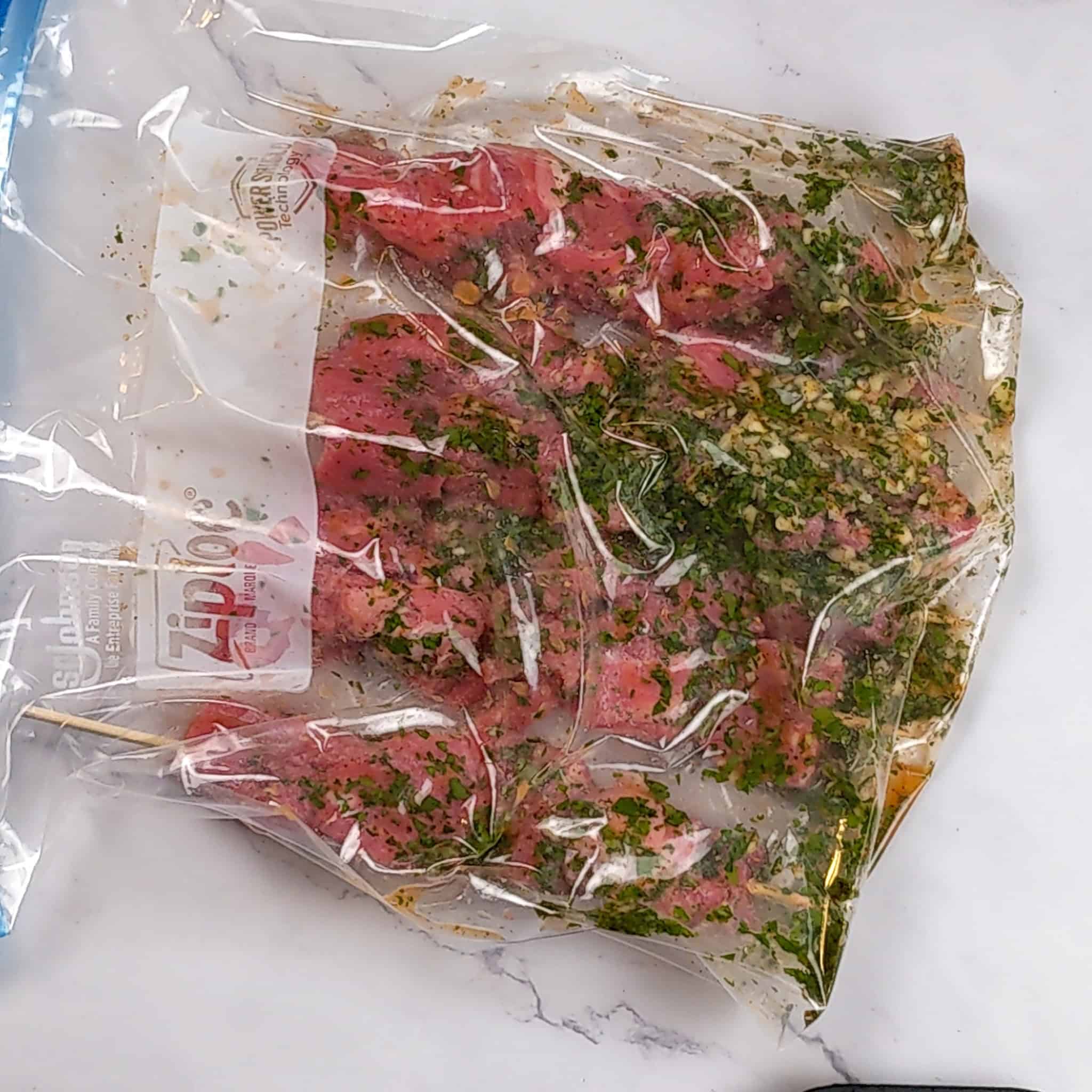 Raw beef skewers and marinade in a resealable bag.