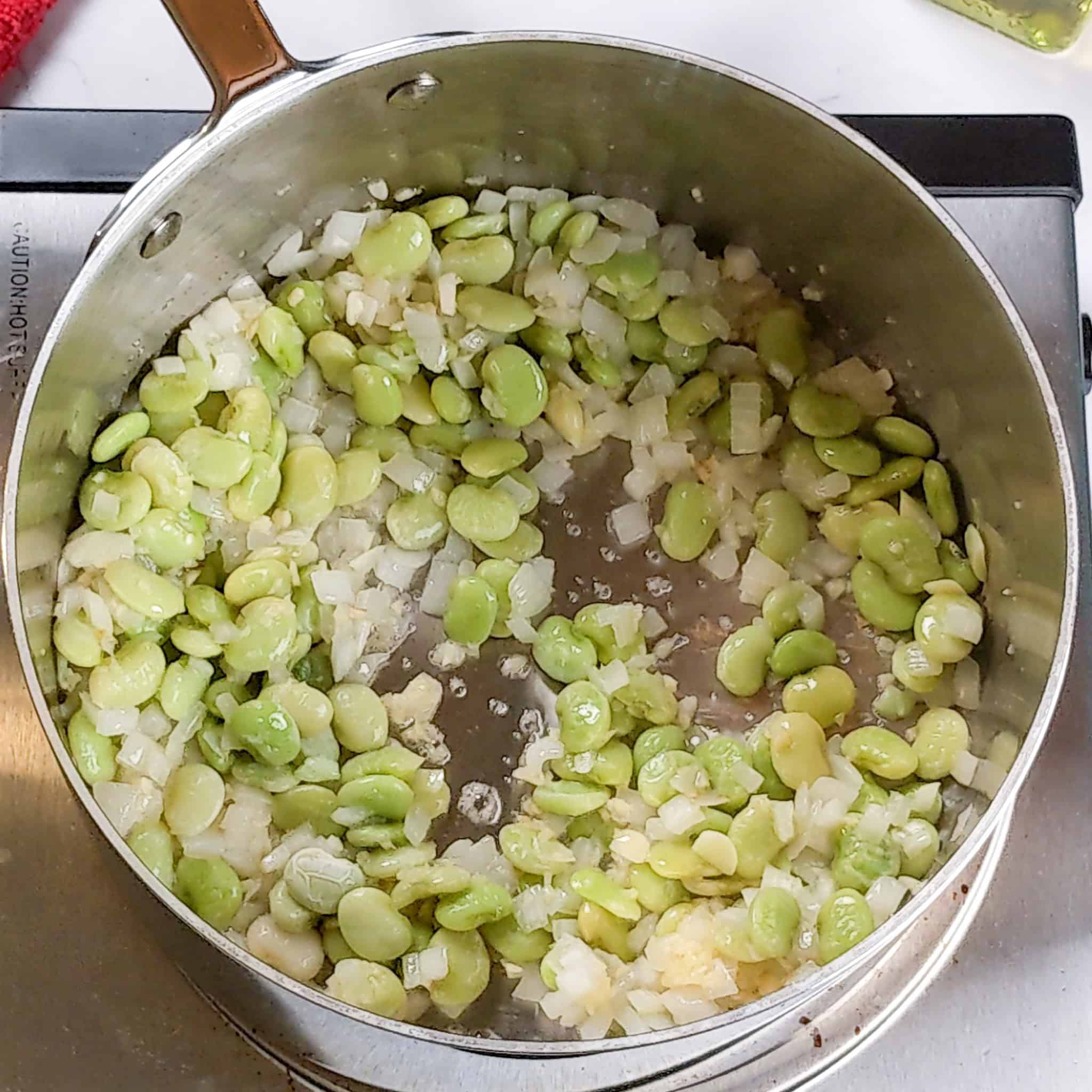 Chopped onion and garlic are sauteed in the sauce pot with lima beans.